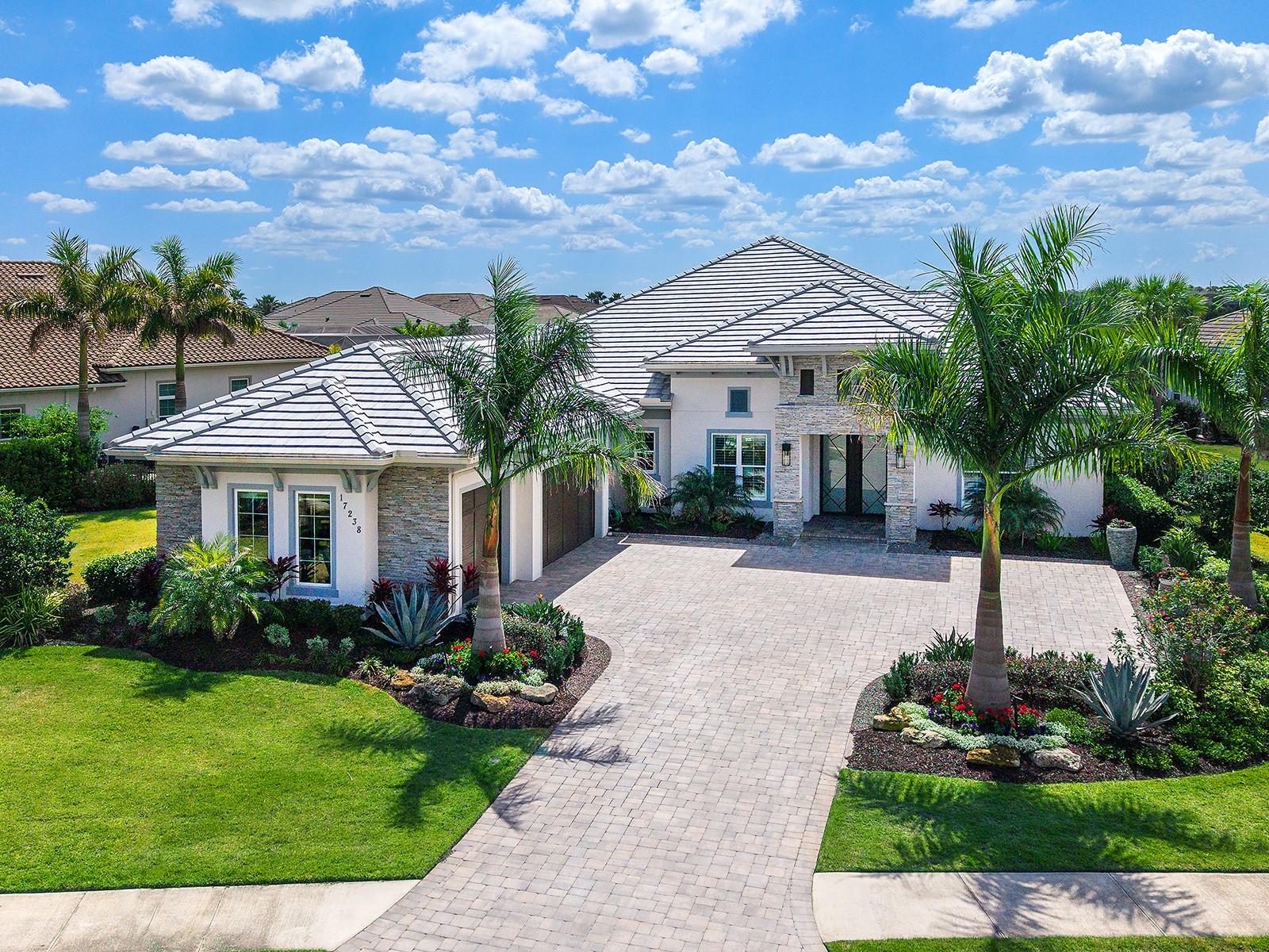 Under contract-accepting backup offers. Set within the gated and prestigious The Lake Club, this Sterling III floor plan with a bonus room offers four bedrooms and four full baths on a 0.53-acre lakefront homesite, blending modern coastal architecture with thoughtful design. A paver driveway, mature landscaping framed by rock-edged planting beds, and stone accents create a welcoming first impression. Throughout the residence, wood-look plank tile flooring, designer lighting, and custom ceiling treatments elevate each space. The foyer features double hurricane-impact doors with geometric iron details and a dual locking system. The great room includes a custom feature wall and expansive sliding glass doors that open to the lanai. The dining area boasts exposed wood ceiling beams and plantation-shuttered windows. The private office includes double glass French doors, a gray wood-trim ceiling with recessed lighting, and built-in shelving and cabinetry. The kitchen balances functionality and design, anchored by a floating island with quartz countertops, storage, and three designer pendant lights above. Custom soft-close cabinetry is complemented by a glass tile backsplash, pull-out drawers, and a hidden trash compartment. A custom wood range hood highlights the five-burner gas cooktop, while the KitchenAid appliance suite and Kohler stainless steel undermount sink support everyday efficiency. A dedicated coffee bar and walk-in pantry with wood shelving provide additional storage and convenience. The adjacent breakfast area overlooks the lake through a large three-panel window, with an additional window facing the outdoor fireplace terrace. Nearby, a wet bar with upper cabinetry, a Brisas wine cooler, and a Sterling sink offers a convenient space for entertaining. The primary suite offers a private retreat with large windows and French doors opening directly to the pool area. Two walk-in closets with custom built-ins provide ample storage. The primary bath includes a dual-sink vanity with quartz countertops, a freestanding Maax soaking tub, and a walk-in glass shower with floor-to-ceiling tile, shelving, and a niche. Three additional guest suites offer walk-in closets and well-appointed bathrooms with a walk-in shower or tub/shower combo surrounds and custom vanities. One of these also serves as the pool bath for easy outdoor access. The bonus room offers flexibility and includes a stone accent wall with a linear fireplace and recessed TV niche, a dry bar with floating shelves, and a large closet with custom doors. The expansive lanai features decorative stone columns, marble pavers, and a linear fireplace with a wood mantle and custom tile surround. The outdoor kitchen includes a grill, hood, sink, beverage cooler, and tile backsplash. The panoramic screen enclosure frames the heated saltwater pool and spa with a sun shelf and fire bowls, while an additional seating area overlooks the lake. The laundry room features cabinetry, a utility sink, and a Whirlpool washer and dryer. The 3-car garage has epoxy flooring, floor-to-ceiling custom cabinetry, and ceiling storage. The home is equipped with impact-rated windows and doors, a security system with video cameras, and two HVAC systems (one with a UV light). Residents of The Lake Club enjoy resort-style amenities including a clubhouse, pool, fitness center, tennis and pickleball courts, dining, social events, and more, all just minutes from Waterside Place, UTC, Mote Aquarium, top-rated schools, and Gulf beaches.