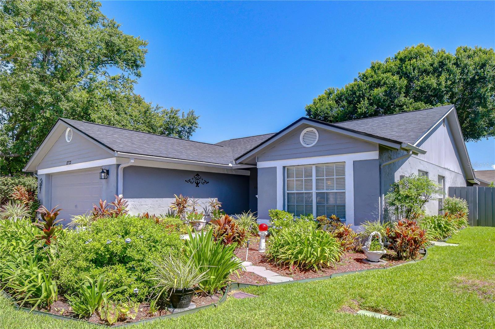 Tucked beneath a canopy of mature oaks in the desirable Fawn Ridge Village community, 8702 Hampden Drive welcomes you home with a meticulously manicured lawn and vibrant, professionally maintained tropical landscaping that frames the entryway in lush greenery and colorful foliage. This 3-bedroom, 2-bathroom, 1,570 square foot home sits on a generous 8,100 square foot lot, offering the perfect blend of comfort, space, and Florida outdoor living.
Step inside through the covered entryway to a bright foyer with tile flooring that flows into a spacious living and dining area featuring laminate wood flooring, vaulted ceilings, and a decorative chandelier. The eat-in kitchen is finished with light wood cabinetry, dark countertops, a full suite of appliances, and a cozy breakfast nook bathed in natural light from a large bay window enhanced with chair rail.
The vaulted-ceiling living room opens through sliding glass doors to a screened-in lanai overlooking a beautifully manicured backyard, lush, green, and shaded by a magnificent mature oak that anchors the space, an ideal setting for relaxing or entertaining year-round in Florida's climate. Thoughtfully landscaped garden beds wrap the perimeter, while the fully fenced yard offers plenty of room to play, garden, or simply unwind, plus a gated side yard for added convenience. A two-car garage with built-in wood shelving provides ample storage, while the home's major systems offers peace of mind with a roof replaced in May 2025, A/C system from 2017, and a water heater scheduled for replacement in June 2026.
Beyond the home itself, Fawn Ridge Village offers low HOA dues, no CDD fees, and resident amenities including a community park, playground, tennis courts, basketball court, and walking trails set among preserved wetlands and ponds. Commuters will love the easy access to the Veterans Expressway and Gunn Highway, putting downtown Tampa, Raymond James Stadium, MacDill Air Force Base, and the Gulf beaches all within easy reach. Everyday convenience is just minutes away too, with Westfield Citrus Park Mall, popular dining options like Olive Garden, Outback Steakhouse, and Mellow Mushroom, plus nearby medical offices and grocery stores all close by. Tampa International Airport is just a short drive away as well.
This is more than a home, it's a lifestyle in one of Tampa's most welcoming communities. Schedule your private showing today and see why 8702 Hampden Drive is the perfect place to call home.