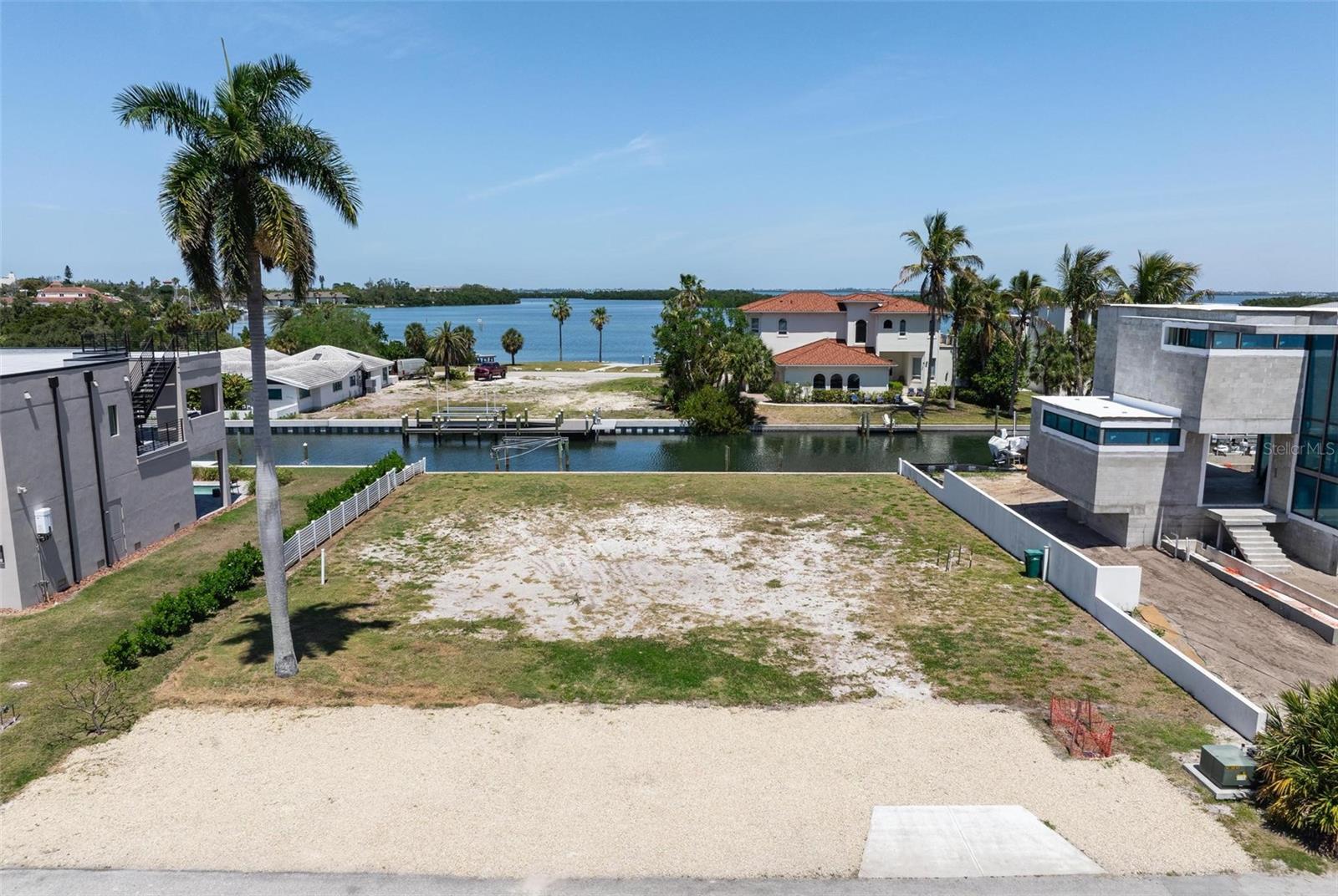 Build your waterfront residence and be perfectly positioned in one of Longboat Key’s most elegant neighborhoods- Longboat Key Estates where sunrise occurs over the Bay while sunset occurs over the Gulf. You will have both and each new day provides unique views. This build-ready lot offers 100 feet of deep-water canal frontage and 117 feet of depth from canal to street where you’ll enjoy direct access to Sarasota Bay. Load up the boat and cruise the bay, the Intracoastal Waterway, and the Gulf of Mexico, with popular waterfront restaurants along the way. Just over the bridge from the mainland, you’re moments from Sarasota —cultural venues, marinas, and everyday conveniences.
A private deeded beach access lies just across Gulf of Mexico Drive, where a shady Tiki Hut welcomes you before taking a few short steps which lead to the gentle Gulf waters and sandy shoreline. The private Tiki Hut is often the venue for neighborhood parties and a frequent gathering spot for sunset seekers!  This vacant lot on Rountree Drive presents a rare chance to enjoy both boating and beachside living in one extraordinary location. Your future dream home could capture panoramic bay and beach views, creating the perfect backdrop for unforgettable Florida sunsets. With no fixed bridges to the Gulf of Mexico except the new very high Ringling Bridge to the mainland, this is truly a boater’s paradise.
Just steps away is Bayfront Park, a beautiful waterfront park overlooking Sarasota Bay. Amenities include picnic tables, tennis courts, lighted pickleball courts, basketball courts, shuffleboard, a kayak launch with rentals, a dog park with separate large- and small-dog areas, a playground, a multipurpose sports field, and a community center offering activities such as yoga and fitness programs.
Located in the heart of Longboat Key, this ready-to-build homesite offers an unparalleled coastal lifestyle. Head north to Center Shops for local favorites such as the Lazy Lobster, Harry's Continental Kitchen, Mar Vista Dockside Restaurant & Pub, and the Shore Longboat Key. Travel south to St. Armand’s Circle for world-class dining, boutique shopping, and vibrant island charm, including Columbia Restaurant, Cha Cha Coconuts, The Daiquiri Deck, Dockside, Chart House, and Tommy Bahama’s Restaurant, among many other fine dining places.
In summary, enjoy championship golf, boutique shopping, award-winning dining, and some of Florida’s most beautiful Gulf Coast beaches, all from your future home in Longboat Key Estates on Longboat Key!
