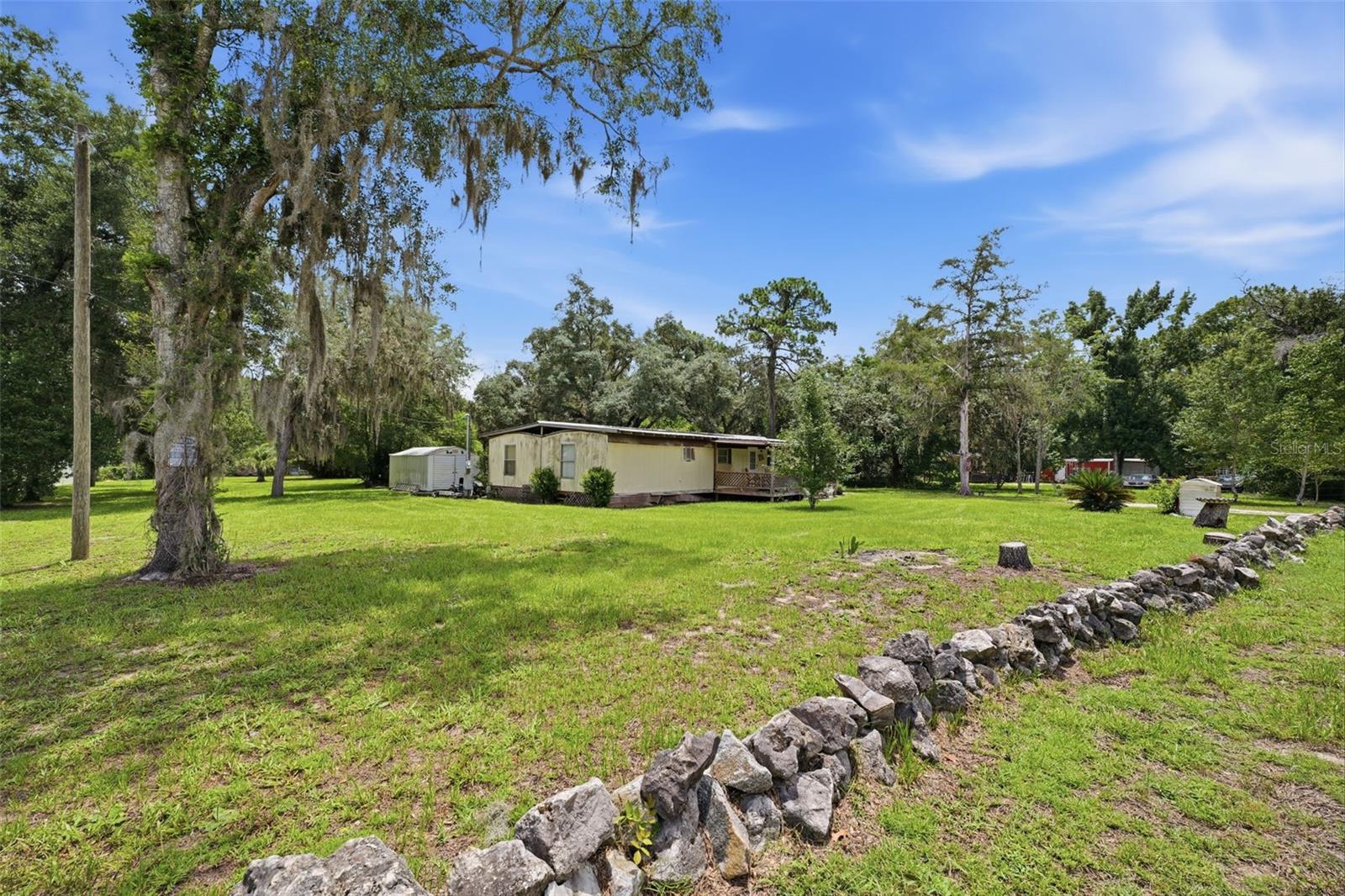 Rare opportunity to own a conveniently located homesite with existing improvements already in place! This property is priced primarily for the value of the land and existing infrastructure, making it an excellent opportunity for investors, builders, or buyers ready to bring their vision to life.

The property features a 1982 manufactured home offering 1,568 living square feet with a metal roof. The home is being sold **as-is** and requires extensive rehabilitation. Due to its condition, the seller will not permit interior showings. Buyers are encouraged to perform their own due diligence regarding the condition of the home and their intended use of the property.

The value continues beyond the homesite with an existing well and septic system, impact fees already paid, a recently replaced well pump, two storage sheds, and a large portion of the property already cleared, helping reduce the time and expense of future improvements.

A unique bonus is the sheriff-approved private shooting range located on the property. Conveniently situated close to shopping, restaurants, schools, and major roadways, this property offers an exceptional opportunity to secure a well-located parcel with valuable infrastructure already in place.