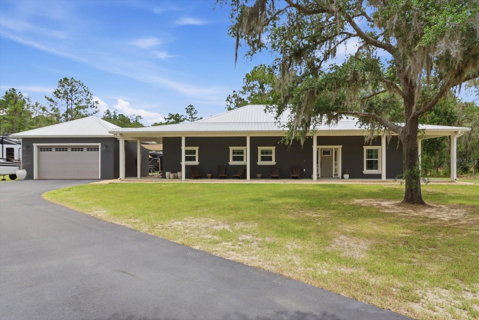Welcome to your private Florida retreat — where 2024 new construction meets 2.32 acres of pure breathing room.

Nestled on 2.32 secluded, tree-shaded acres, this nearly new 2024 custom-built concrete block home blends modern luxury with true outdoor living. With 3 bedrooms, 2.5 bathrooms, and over 2,130 square feet of thoughtfully designed space, it’s ideal for growing families, multi-generational living, or anyone ready to escape the hustle without sacrificing comfort or style.

Step inside to an open, light-filled floor plan with quality finishes throughout. The chef’s kitchen anchors the home with a quartz waterfall island, stainless steel appliances, and custom wood cabinetry, flowing effortlessly into the dining and living areas beneath a striking tray ceiling. The split-bedroom layout places the primary suite privately apart from the secondary bedrooms — complete with an oversized walk-in closet and a spa-inspired en-suite bath featuring a walk-in tiled shower with a pebble-stone floor and dual vanities.

Outside is where this property truly shines. Nearly 2.5 acres of peaceful, wooded privacy offer endless room to garden, play, ride ATVs, host bonfires, or let pets and kids roam free. A full wraparound covered porch is the perfect spot for morning coffee or evening unwinding while you take in the serene surroundings.

Bring all your toys — the property is equipped with RV hookups, making it easy to host family and friends or park your own RV for weekend adventures. The oversized 2-car garage adds even more room for vehicles, tools, or recreational gear.

Built in 2024 with durable concrete block construction, a metal roof, and impact windows, this home offers the energy efficiency and peace of mind that come with newer construction — with none of the wait.

If you’ve been searching for a move-in-ready home that combines privacy, acreage, modern construction, and an outdoor lifestyle, this exceptional property checks every box. Schedule your private showing today and experience country living with all the comforts of a beautiful new home.