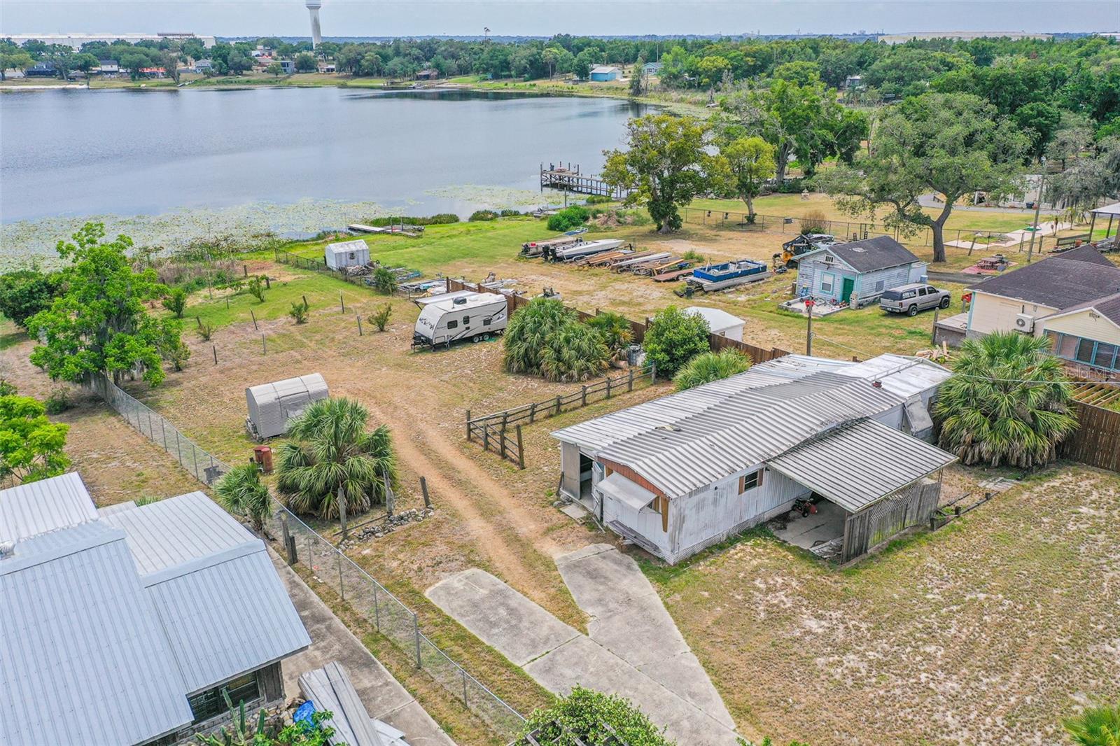 One or more photo(s) has been virtually staged. Enjoy the beauty of true Florida lakefront living on private Lake Lucerne! Situated on just over half an acre, this fully fenced waterfront property offers peaceful water views, breathtaking sunsets, and endless opportunities for fishing, boating, kayaking, or simply relaxing by the lake. Surrounded by mature trees and natural beauty.

This versatile property features a grandfathered-in 3-bedroom, 2-bath single-wide mobile home offering excellent flexibility and future potential. The home includes tiedowns, a slab foundation, power, air conditioning, and a covered and screened patio area perfect for relaxing outdoors while enjoying the peaceful lakefront setting. The metal roof adds durability and functionality, while water has not been connected to the mobile home during the seller’s ownership the existing structure creates opportunities for continued use, renovation, replacement, or redevelopment. The property is grandfathered to allow replacement of the existing mobile home or the opportunity to build your own custom lakefront home. The seller is also including custom home blueprints valued at approximately $3,000 to help bring your vision to life.

A major BONUS is the included 2017 KEYSTONE PASSPORT UlLTRA LITE 195RB CAMPER overlooking the lake, offering a comfortable turnkey setup perfect for weekend getaways, seasonal use, or full-time living. The camper is fully furnished and includes all furniture, décor, kitchenware, appliances, manuals, and household contents. Features include heat and air conditioning, working appliances, newer awning, newer tires including spare tire, backup camera, load distribution hitch, small grill, coffee maker, booth-style dining area, full kitchen, cozy sleeping area, and scenic lake views throughout.

Additional property features include mature fruit trees such as banana, avocado, pecan, persimmon, and peach, along with a private well, septic system, metal storage shed, and convenient frontage on a main road while still maintaining a quiet waterfront atmosphere.

Located in Winter Haven’s desirable lake region, this property is approximately 25 minutes from LEGOLAND Florida Resort and about 35 minutes from Walt Disney World. Whether you’re looking for a waterfront getaway, investment opportunity, or future dream homesite, this unique property captures the charm of Old Florida living while offering privacy, flexibility, and future potential.