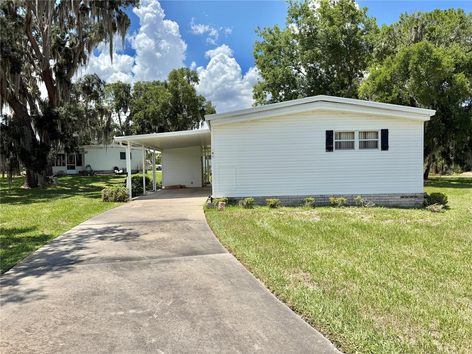 Welcome to your peaceful lakeside retreat! This spacious 2-bedroom, 2-bath home is tucked away on a private cul-de-sac lot and offers serene views of Lake Serenity from both the living room and the bright Florida room. Enjoy the tranquil setting while still having plenty of space to relax, entertain, and make the home your own. Filled with character and charm, this home presents the perfect opportunity to preserve its classic 1970s style with a few modern touches or reimagine the space with a complete renovation. The spacious primary suite features a walk-in shower, while the guest bath includes a tub for added convenience. Recent updates include upgraded vinyl siding, a new electrical panel (2025), and a newer carport (2009). The long driveway provides ample parking, and the private lot offers a sense of seclusion that’s hard to find. Whether you’re searching for a year-round residence, seasonal escape, or investment opportunity, this inviting home offers beautiful lake views, generous living space, and endless potential..................Hawthorne at Leesburg is an active, resident owned, 55+ cooperative, waterfront, gated community, with beautifully landscaped grounds, lakes with illuminated fountains and a relaxing and comfortable gazebo. The affordable monthly maintenance fee of $397 includes water, sewer, lawn mowing, private emergency services and storage space for recreational vehicles, boats, trailers and much more! The beautiful clubhouse is complete with a full-time program coordinator, more than 100 different activities and seating for 550. It has a hospitality lounge, card rooms, craft rooms, billiard room, fitness center, library, fine arts room and many more. There is excellent fishing, outdoor geo-thermally heated pool and two enclosed therapeutic pools. Hawthorne boasts a private marina monitored by an electronic security system with over 120 boat slips and access to the Harris Chain of Lakes and beyond.