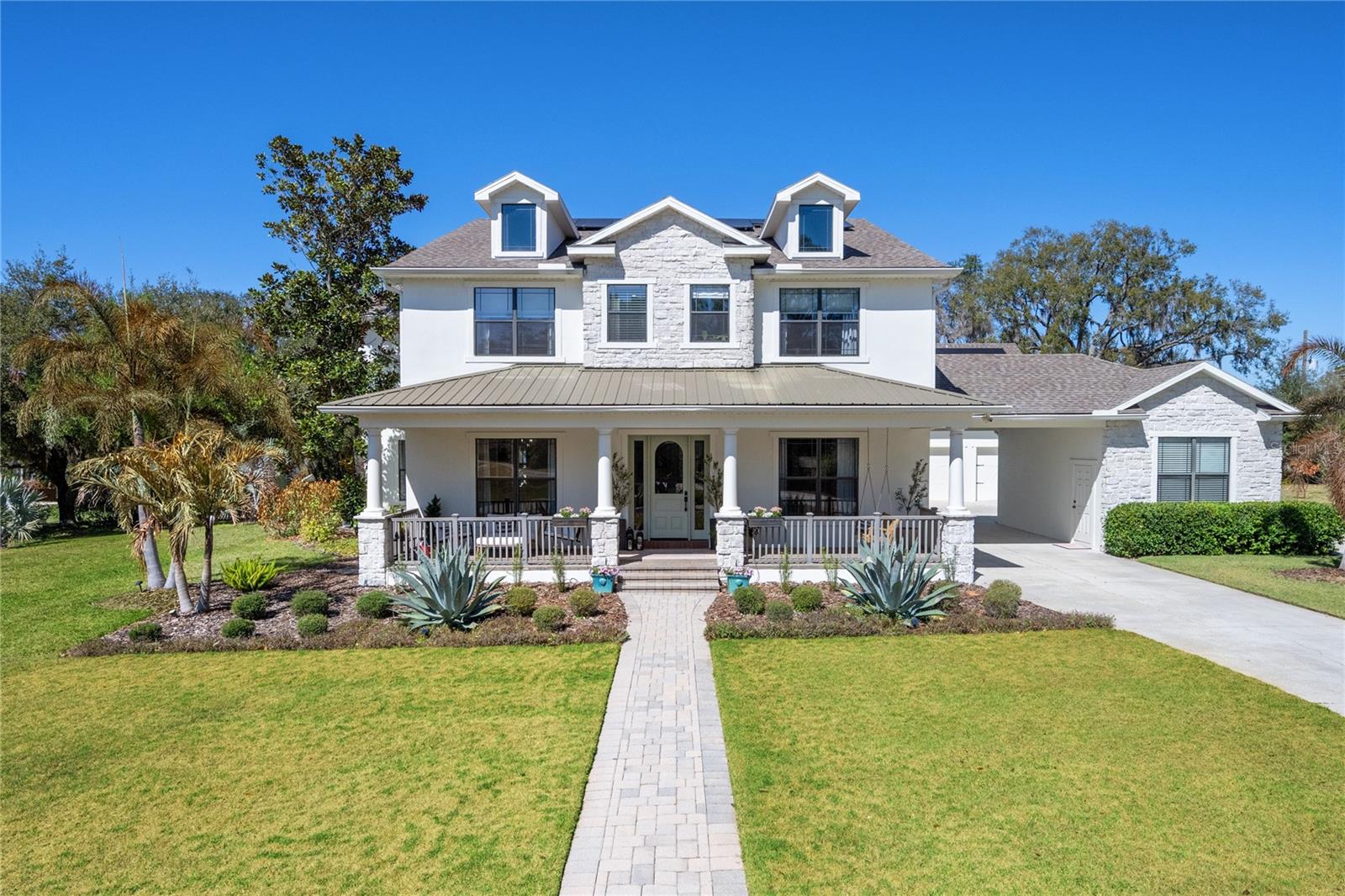 Privately gated and positioned at the end of a wooded cul-de-sac, this modern farmhouse estate spans nearly five acres with tranquil lake views and built-in hiking trails, offering a rare sense of privacy just minutes from Lake Nona.
You are welcomed by a sprawling front porch that immediately sets the tone for relaxed, refined living. Inside, a spacious entry showcases European white oak flooring throughout. The layout is intentional, with a great room on one side and a formal dining room on the other.
Renovated in 2024 with high end improvements, the home blends clean architecture with warm finishes. The kitchen features custom inlay cabinetry with LED underlighting, a leathered granite island, Venetian plaster hood, hidden walk in pantry, and a separate coffee nook with beverage refrigerator. The appliance package includes a 43 inch La Cornue induction range, 36 inch Monogram refrigerator and freezer columns, Fisher and Paykel double drawer dishwasher, ice maker, and multiple beverage centers.
The layout offers a first floor bedroom with a private en suite bath, while the remaining bedrooms are positioned upstairs for added privacy. The primary suite features a private balcony overlooking the lake and backyard. The spa inspired bath includes double vanities, steam shower, freestanding soaking tub, smart toilet, and a custom closet system.
A separate staircase leads to an expansive loft with an additional bonus bedroom, creating flexible space for a media room, office, gym, or guest suite.
Outdoor living includes a marble pool deck, custom pool and spa with water feature, summer kitchen, and dedicated pool bath. The property also includes a 1,000 gallon buried propane tank and paid off solar panels.
Additional highlights include a five car garage and an additional bay perfect for a workshop or gym. Having two laundry rooms, a custom mudroom, whole home water filtration, two tankless water heaters, two new AC units, a 2022 roof, and a whole house generator make the home even more impressive. Private acreage, lake views, and refined modern farmhouse design just minutes from Lake Nona create a rare opportunity for secluded luxury with everyday convenience.