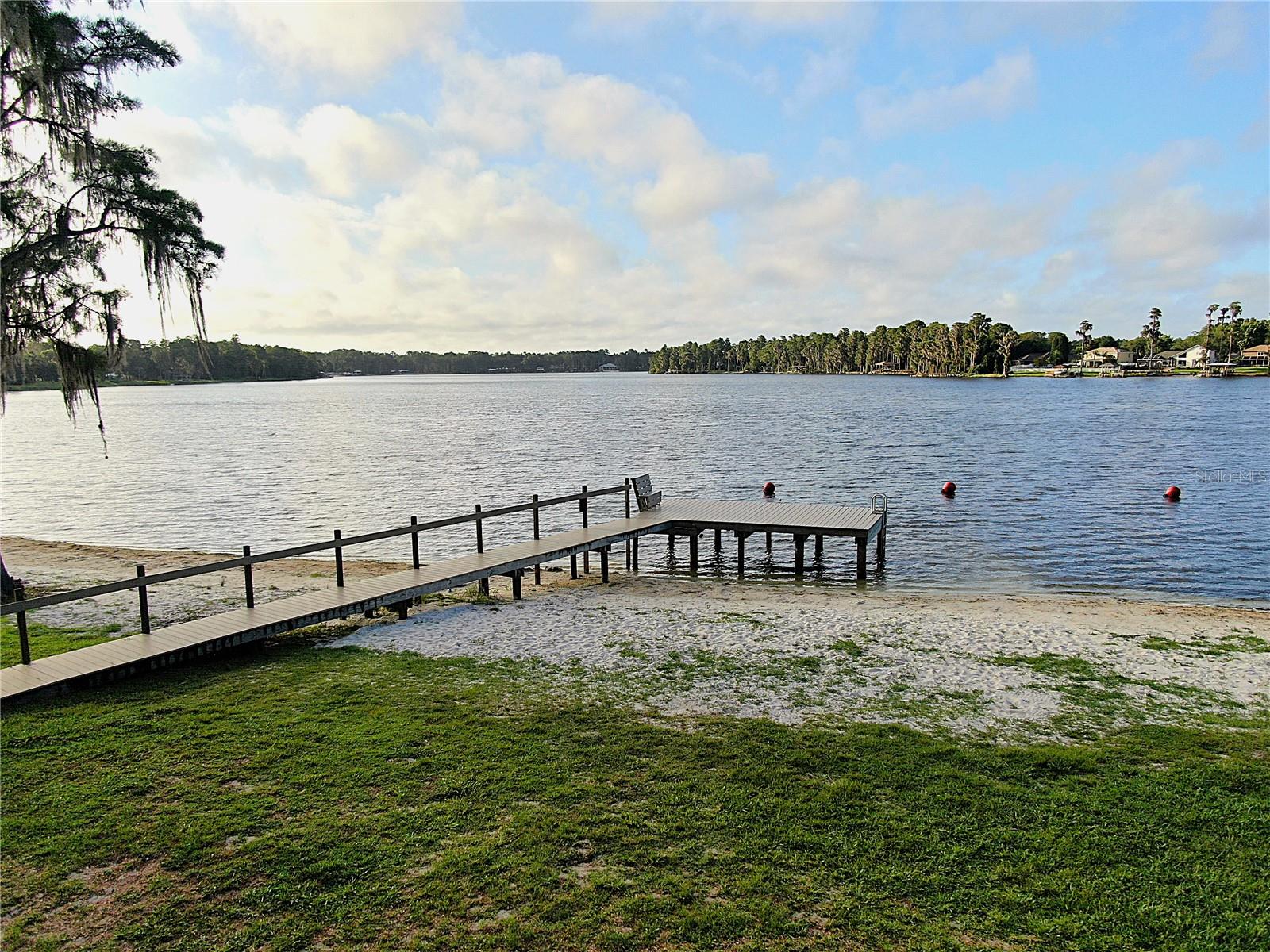 Discover Your Dream WATERFRONT PROPERTY on a CHAIN of 3 SKI SIZED LAKES
Welcome to an unparalleled opportunity to own a piece of paradise in a gated community that offers the finest in lakefront living. This large, waterfront lot is nestled in a park like community on not one, but three ski sized connected lakes, creating an aquatic haven for water sports enthusiasts and nature lovers alike. A perfect place for boating, water skiing, fishing, and kayaking. The property already includes a covered dock, well, septic tank, and drain fields.
This unique community designed for relaxation and recreation. Residents enjoy a private beach area complete with a boat ramp, Multiple docks, grills, picnic tables, sand volleyball court, horseshoes, and a designated swimming area. Whether you’re looking to spend a lazy afternoon basking in the sun or hosting a lively barbecue, this private beach area has it all.
Children will delight in the community playground, featuring a basketball court and ample space for play. The entire community is golf cart friendly, allowing for a leisurely ride through the picturesque surroundings, especially to the beach area and other amenity areas as well.
This idyllic community is dotted with majestic oak and cypress trees, creating a park-like atmosphere that invites you to connect with nature. As
you meander through the tree-lined streets, you'll appreciate the tranquility and beauty that defines this unique locale. The gated entrance ensures privacy and security, giving you peace of mind as you enjoy the numerous amenities.
One of the standout features of this property is that all impact fees have already been paid, streamlining the building process and saving you time and money. 
Whether you’re an avid boater, a fishing enthusiast, or simply someone who enjoys an active lifestyle, this community caters to all your recreational needs. The lakes are perfect for skiing, fishing, & kayaking, while the community spaces provide endless opportunities for outdoor fun. The convenience of the private boat ramp and fishing dock means you can easily indulge in your favorite water activities.
This community fosters a welcoming and vibrant atmosphere. Neighbors become friends at the beach area, children play together at the playground, and families gather for barbecues and picnics. The golf cart-friendly design encourages a sense of camaraderie as residents explore the community and enjoy the natural beauty together.
With its prime location on a three ski-sized lakes, this property is ready for you to build your dream home. Experience the lifestyle you’ve always envisioned—where every day feels like a vacation.
Schedule to see this property today