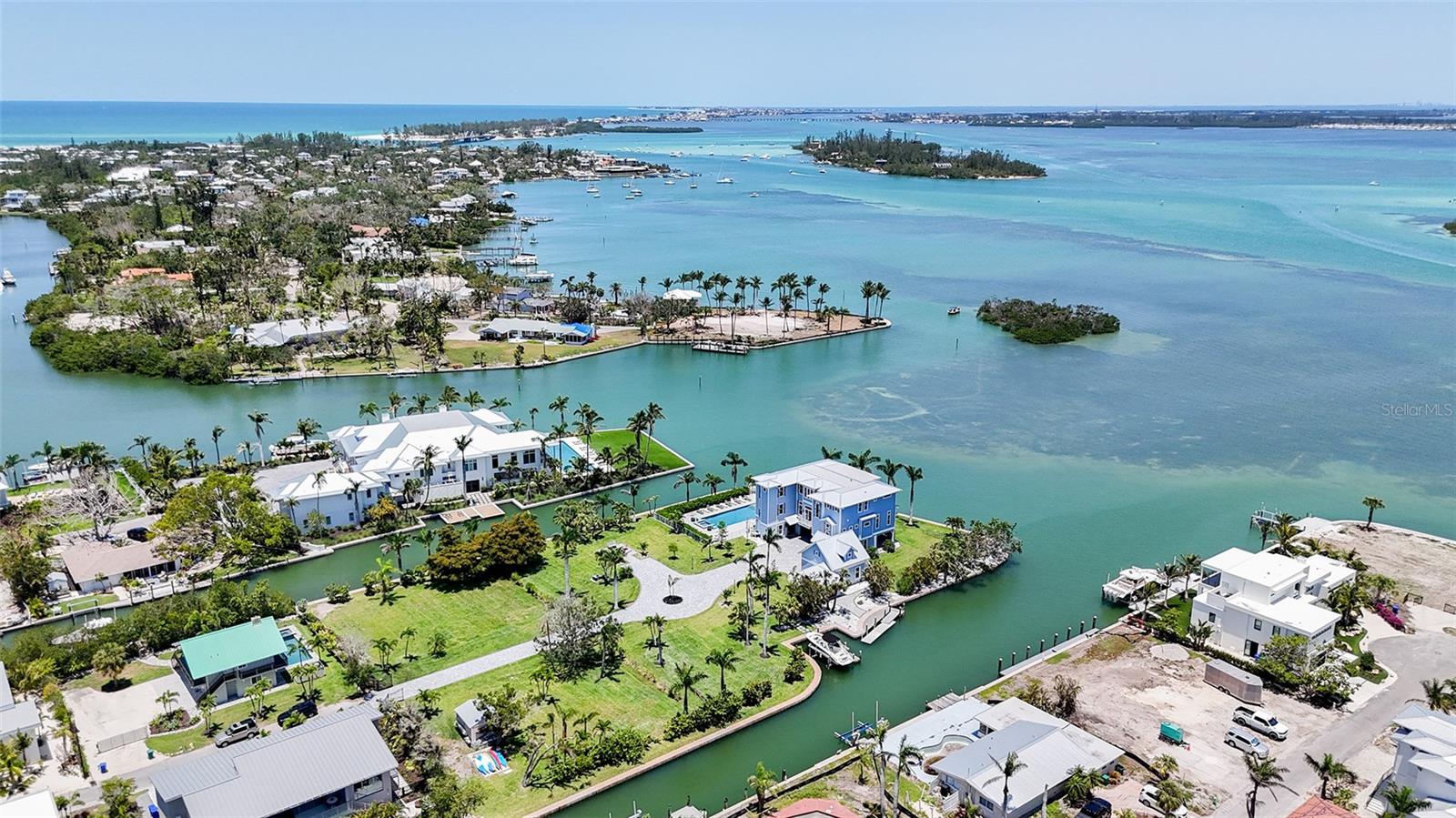 This stunning Bayfront estate delivers over 480 feet of pristine Bayfront waterfront on a  prime point property. True Longboat Key gold. Special features of this home include five bedrooms, five full bathrooms, hardwood floors, sky-high ceilings plus walls of glass. The home opens to multiple covered terraces built for soaking in endless Bay views and the best of Florida living at its finest. The open-concept layout blends indoor comfort with outdoor style, perfect for hosting or unwinding in total privacy. The kitchen is sleek and spacious with high end Wolf package and Sub Zero ready for gourmet meals or casual bites with a view.  The adjoining family room also features a large stone fireplace. The primary suite is a retreat all its own with private terrace access, spa-style bath and water views that never quit. Outside, the lifestyle really takes off. A large Bayfront resort-style pool with a hot tub anchors the backyard, surrounded by multiple fire pits perfect for evening gatherings under the stars. Need space for guests? A separate guest house is available to design to your personal touch, offers total privacy and comfort, ideal for hosting family or friends without sacrificing your own space. This estate isn’t just a home it’s a waterfront playground built for bold living.  There's kayak storage and room for multiple docks and all your water toys. The new seawall built in 2010 adds peace of mind. There is a four car garage. This North Longboat property is a must see for anyone seeking a luxurious lifestyle combined with natural beauty. With its modern amenities, prime location, and stunning views, it stands out as a dream home. Don’t miss the opportunity to make this exquisite residence your own. This north Longboat location is near many outstanding restaurants and Anna Maria Island. Watch dolphins and manatees and so many Florida birds glide past your backyard. The azure waters of the Gulf of Mexico and the beach are just steps away.