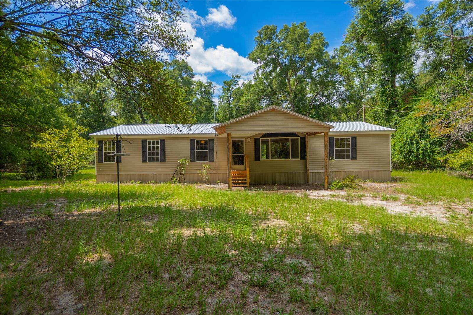 If you’ve been dreaming of five acres, fresh air, and enough room that your nearest neighbor isn’t borrowing your lawn mower, welcome home. Tucked beneath a canopy of mature oaks in High Springs, this 3 bedroom, 2 bath home offers over 1,600 square feet and the kind of privacy that’s getting harder to find. Inside, you’ll find a spacious split floor plan with multiple living areas, a gas fireplace for cool Florida evenings (yes, we have a few), and a kitchen with enough cabinet space to finally justify buying every small appliance you’ve been eyeing. Recent updates include fresh interior paint, new toilets, recently cleaned HVAC ducts, new front steps, a newer refrigerator, and a water treatment system. Outside is where this property really shines. Five wooded acres provide room for gardens, chickens, bonfires, ATVs, or simply enjoying the peace and quiet while watching the frequent visits from large 7/8pt bucks and other wildlife. A storage shed, 4-inch submersible well, and sturdy ¾-inch plywood subfloor add practical value. Best of all, you’re only about 7 miles from Ginnie Springs and the Santa Fe River, making it easy to spend your weekends floating crystal-clear springs instead of sitting in traffic. Country living, room to roam, and endless possibilities, just bring your imagination (and maybe a kayak).