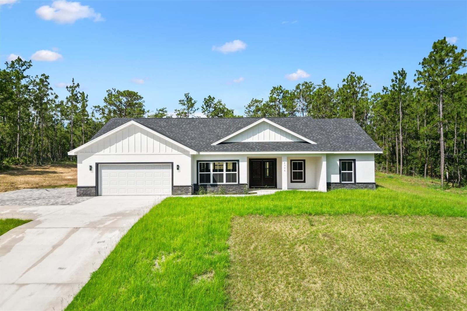 Welcome to this stunning modern farmhouse-style new construction home in the desirable Oak Hill subdivision of Wildwood, FL. Nestled in a quiet, rural setting on a spacious 1-acre homesite, this beautifully designed 3-bedroom, 2-bath home with a den/office offers the perfect blend of privacy and convenience. Enjoy peaceful country living while being just minutes from The Villages, top-rated schools, shopping, dining, and more. Built with block and stucco construction, this home delivers durability, energy efficiency, and low-maintenance living for years to come. Offering 1,906 square feet of living space, the thoughtfully designed floor plan includes an oversized garage, covered rear lanai, and an interior laundry/mud room. Step inside to an inviting open-concept layout featuring high ceilings, luxury vinyl plank flooring, recessed lighting, and 5” baseboards, all wrapped in a clean, modern aesthetic. The kitchen serves as the heart of the home, showcasing a large center island, Farmhouse Single Basin sink, custom wood cabinetry, stainless steel appliances, under-cabinet lighting, tile backsplash, walk-in pantry, and a cozy dining nook—perfect for everyday living and entertaining. The primary suite is a true retreat with a spacious walk-in closet and a spa-inspired ensuite featuring a freestanding soaking tub, walk-in tiled shower, and ample cabinet space. The secondary bedrooms are generously sized with walk-in closets and share a well-appointed guest bath with a tiled shower. The den/office offers flexible space ideal for a home office, media room, or even an additional bedroom. Outside, the property continues to impress with its expansive lot and serene surroundings—no expense was spared in creating this beautifully crafted home. This is a rare opportunity to own a brand-new home with space, style, and location all in one. Schedule your private tour today—this one won’t last!