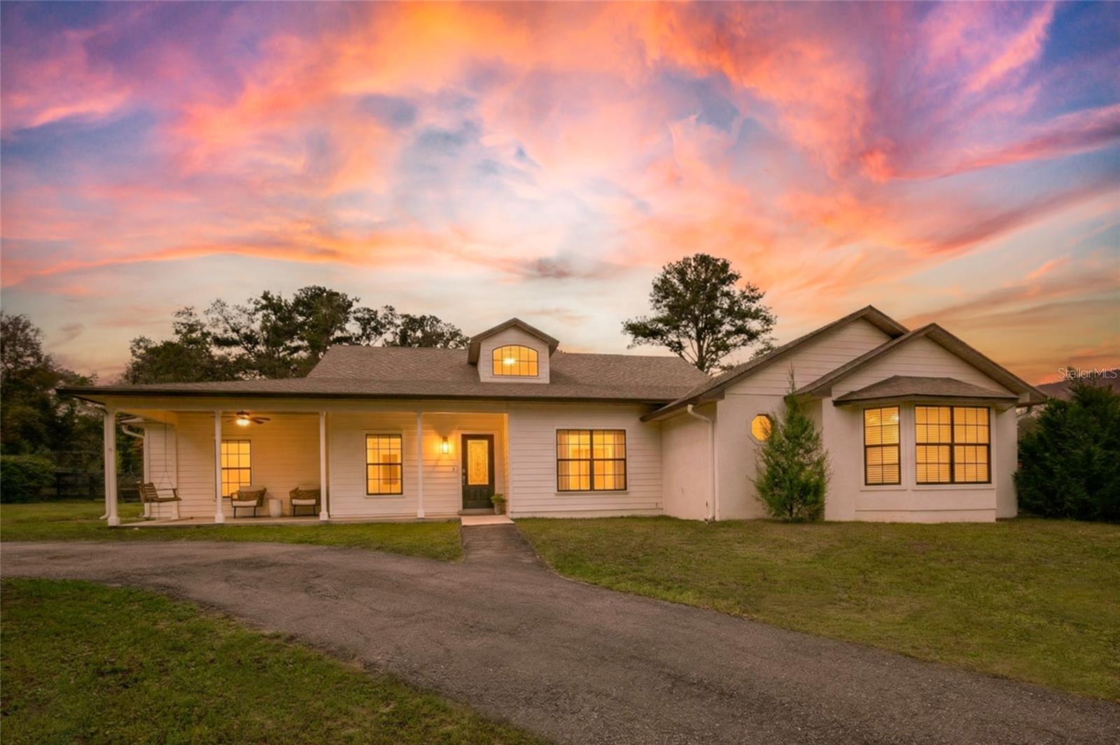 Exceptional design and thoughtful planning define this beautifully appointed equestrian property where well-equipped horse facilities and comfortable living spaces come together to create a truly turnkey horse estate. At the center of the property is a thoughtfully designed main barn built with both functionality and airflow in mind. A striking 16-foot pavered center aisle leads to eight spacious 12' x 12' stalls, each with attached run-ins that provide flexibility and excellent ventilation. The barn is equipped with oversized aisleway fans, automatic waterers, lighting and electrical outlets in every stall, two 12' x 12' wash racks, a feed room, and eight walk-in tack lockers for organized storage. An air-conditioned kitchenette with hot and cold water adds convenience for daily barn operations. The layout also allows the option to add an additional stall or expand hay and feed storage if desired. An additional two-stall barn with wash rack is located within one of the paddocks.
The riding facilities are equally impressive. A full-size 100' x 200' laser-leveled competition dressage arena with fiber footing and irrigation provides a consistent surface ideal for schooling and training. A viewing stand with additional deck space overlooks the arena, offering a comfortable place to observe riding activity. Five shady paddocks with irrigation and no-climb fencing provide generous turnout space. A small trail loop winds through the back of the property, and designated areas are in place for manure composting and disposal. Additional improvements include a pole barn with 14-foot ceilings and adjacent parking pad providing excellent space for trailers, tractors, or equipment. The detached 50' x 25' garage/workshop features two roll-up doors and multiple power options including 120V 30-amp, 240V 50-amp, and 125V 30-amp service. Accessed through two electric gates, the residence offers privacy and a welcoming sense of arrival. The main home features four bedrooms, three bathrooms, and a dedicated office, along with a private one-bedroom, one-bath in-law suite with separate entrance, living room, and kitchenette. Stamped concrete floors run throughout the main living areas and are complemented by abundant natural light. The living room features a gas fireplace that creates a warm focal point for gathering. A spacious family room with built-in bench storage offers flexible space ideal for a media room, exercise area, or additional living space. The primary suite includes a walk-in closet and ensuite bath with garden tub. Bedrooms two and three share a Jack-and-Jill bathroom, while bedroom four is located near an additional full hallway bath. Outdoor living spaces include a raised garden area and a covered patio overlooking a tranquil goldfish pond that leads to the swimming pool, creating a peaceful setting for relaxing or entertaining. Located in an area known for its equestrian lifestyle, the property offers convenient access to riding trails in nearby Seminole State Forest and Ocala National Forest. It is also within comfortable driving distance of popular show grounds including Clarcona Horse Park, Grand Oaks, and the Florida Horse Park. Shopping, dining, and everyday conveniences are just minutes away, while Ocala, Orlando, area airports, and Florida’s east coast beaches remain easily accessible.