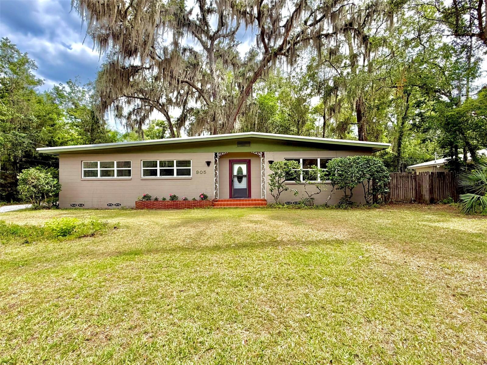 Classic mid-century home in Gainesville's Creekside neighborhood! This well-maintained concrete block home has no HOA and is rich in character, featuring original terrazzo floors ready to shine, complemented by wood flooring throughout. Metal roof (2013), updated windows, plumbing and water heater (2020), and HVAC (2010). Enjoy Florida living from the spacious screened back patio, complete with a generous storage room. The oversized backyard is shaded by a magnificent live oak and other mature trees, creating a peaceful setting with plenty of room for entertaining, gardening, pets, or play.
Inside, original mid-century pocket doors between the kitchen/dining area and living room offer the flexibility of an open-concept layout or the option to create separate living spaces for added privacy when desired. Ideally located with convenient access to the University of Florida, downtown Gainesville, shopping, parks, and schools, this home combines the durability of concrete block construction with timeless mid-century appeal
