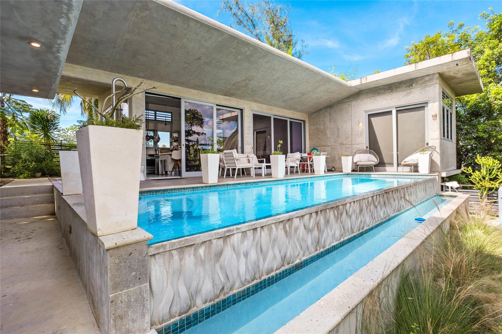 Casa Sol – A Bespoke Brutalist Retreat in Puntas, Rincón Discover Casa Sol, a striking modern residence in the heart of Puntas, just a short walk to iconic Sandy Beach. Designed with a refined cement brutalist aesthetic, this 4-bedroom, 3-bathroom masterpiece blends bold architecture with relaxed coastal luxury. Step into expansive open-concept living framed by clean lines, polished concrete, and oversized windows that invite natural light throughout. The home’s elevated position offers partial ocean views, creating a serene backdrop from sunrise to sunset. At the center of the outdoor experience is a stunning infinity pool surrounded by a sleek deck ideal for sunbathing, entertaining, or unwinding after a day on the beach. An outdoor shower enhances the tropical lifestyle, offering convenience and resort-style comfort. Equipped with solar panels, battery backup and a whole house water filtering system, Casa Sol delivers sustainable, off-grid-ready living without sacrificing modern conveniences. Property Highlights: - Modern cement brutalist design with luxury finishes - 4 bedrooms / 3 bathrooms - Infinity pool with panoramic ambiance - Expansive deck + outdoor shower - Partial ocean views - Solar panels with battery system - Water filter system - Short walk to Sandy Beach, surf, dining & nightlife - Ideal for full-time living, vacation home, or high-end rental A rare blend of cutting-edge design and coastal ease, Casa Sol offers a private sanctuary in one of Rincón’s most desirable neighborhoods.