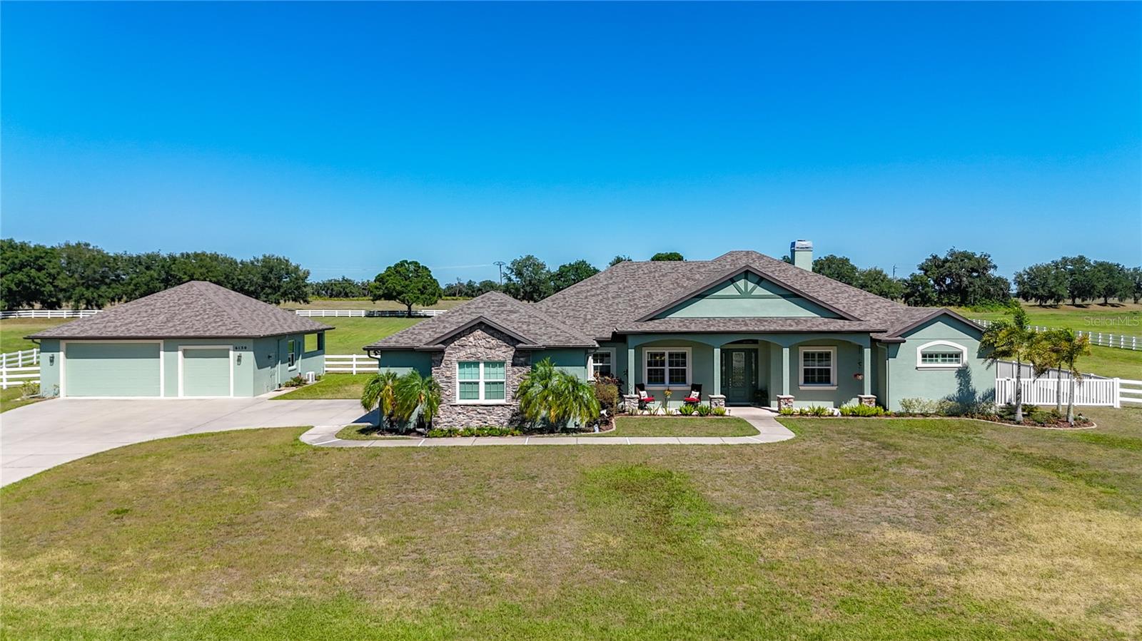 Set on 5 beautifully fenced acres within the highly desirable Rural community of Foxbrook, this exceptional custom-built estate by McKenzie Homes combines timeless craftsmanship, modern efficiency, and peaceful country living. Designed with both elegance and functionality in mind, this spacious 4-bedroom, 3-bath residence offers an inviting great room floorplan with soaring 10 to 12-foot ceilings, porcelain wood-look tile throughout the main living areas, a dramatic coffered ceiling, and a warm wood-burning fireplace that serves as a stunning focal point of the living space.  French doors in both the great room and owner’s suite open to the covered and screened lanai, seamlessly blending indoor and outdoor living spaces while inviting in tranquil views of the surrounding acreage. Window shutters throughout the home add style and functionality while enhancing the home’s refined design.
The gourmet kitchen is beautifully appointed with rich solid wood traditional cabinetry featuring raised panel detailing, upper glass-pane accent cabinets, custom tile backsplash, undercounter and over-cabinet lighting, extensive storage drawers, and a spacious closet pantry. Stainless steel appliances include a range, built-in oven and microwave, and French door refrigerator. Casual dining is easily accommodated with breakfast bar seating and a sunny dinette area, while the formal dining room provides the perfect setting for entertaining and holiday gatherings.
The spacious owner’s retreat offers a luxurious private escape complete with tray ceiling, ceiling fan, French doors to the lanai, and two oversized custom walk-in closets. The ensuite bath features dual granite vanities with abundant drawer storage, soaking tub, walk-in shower, linen closet, and private water closet.
Designed with privacy in mind, the home also features a separate guest wing where bedrooms two and three are tucked away off their own private hallway. Both guest bedrooms are generously sized and appointed with ceiling fans, and extended closets, while sharing a well-appointed full bath, creating a comfortable, private space for family or guests. The flexible fourth bedroom is ideally positioned near the front of the home and features its own ensuite bath, making it perfect as a private guest suite, home office, or den.
Practicality meets luxury in the oversized utility room featuring granite countertops, folding space, and additional storage closet. Car enthusiasts, hobbyists, and equestrian buyers alike will appreciate the attached oversized 3-car garage in addition to the detached 2.5-car garage with air-conditioned tack room/exercise room/or just plain wonderful storage! The rear of the detached garage is a covered area has been designed as a loafing shed (or covered patio), while the fenced pasture is ready for horses and country living at its finest.
Built with exceptional quality and energy-efficient features, the home includes hurricane impact windows & doors along with Icynene spray foam insulation designed to provide superior comfort, sound reduction,& significant energy savings year-round. Significant recent updates include new roofs installed in 2025 & complete exterior repainting in 2026, offering peace of mind & enhancing the home’s beautiful curb appeal.
Residents of Foxbrook enjoy estate-sized homesites and a warm community atmosphere with the convenience of nearby schools, shopping, major highways and Florida’s renowned Gulf Coast beaches.