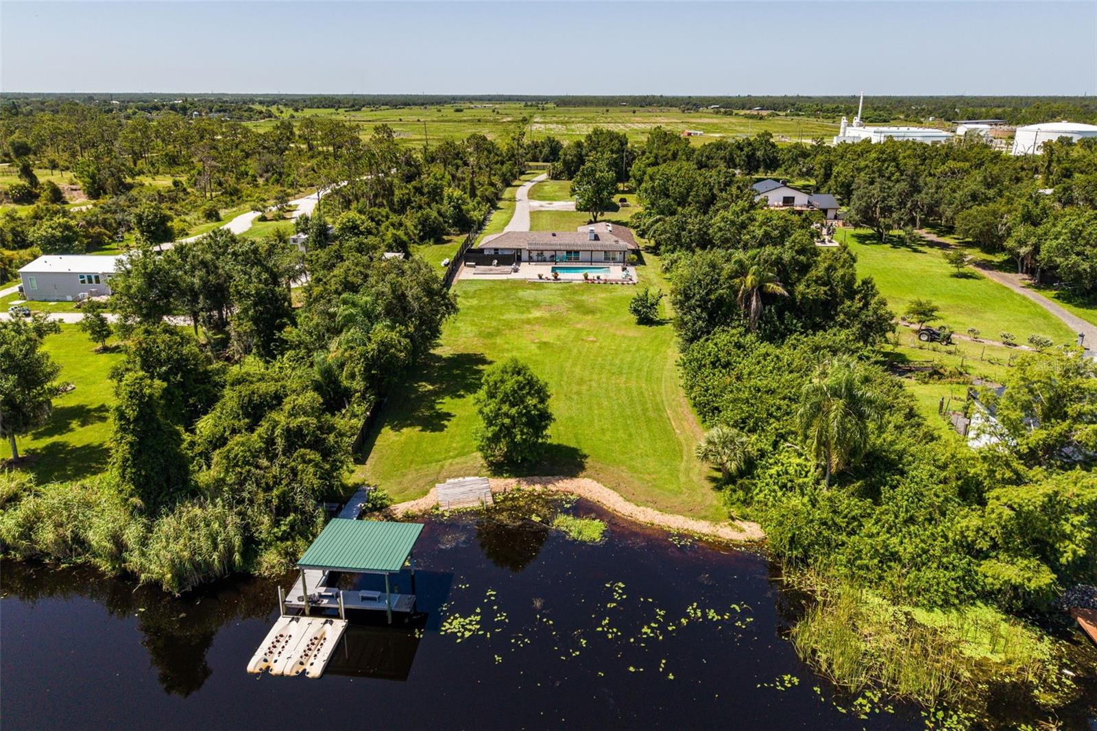 Escape to your own private waterfront paradise where timeless Old Florida charm meets modern comfort. Nestled on 2.35 picturesque acres along the peaceful shores of Shell Creek lake, this beautifully remodeled 4-bedroom, 2-bathroom estate with a new, durable Brava composite roof & impact resistant windows offers an exceptional opportunity to enjoy nature, privacy, & an unmatched waterfront lifestyle. From the moment you step inside, you'll be captivated by the spacious great room floor plan, thoughtfully designed for both everyday living and entertaining. The inviting living area flows seamlessly into a warm flex space featuring a stunning double sided wood-burning fireplace that's perfect for a dining area or game room. The beautifully updated kitchen is the heart of the home, showcasing attractive cabinetry, granite countertops, stainless steel appliances, & an open design that overlooks the living areas & expansive lanai, making entertaining effortless. Wake up each morning in the tranquil primary suite, where a cozy fireplace creates the perfect retreat. Sliding glass doors frame breathtaking views of the heated pool and sparkling waterfront, bringing the beauty of nature indoors. Two additional guest bedrooms provide comfortable accommodations, while the beautifully renovated bathroom features a spacious tiled walk-in shower with seamless glass and a stylish modern vanity. Adding incredible flexibility is the private studio apartment with its own entrance, attractive epoxy floors, renovated bathroom with copper ceiling, all-in-one washer/dryer & plumbing already in place for a future kitchenette. Whether you're looking for a guest suite, rental opportunity, home office, artist's studio or hobby room, this versatile space offers endless possibilities.
Step outside and discover your own backyard oasis. The expansive paver patio with a charming pergola surrounds the heated pool with saltwater system, creating the perfect setting for relaxing, outdoor entertaining or evenings under the stars. The fully fenced yard provides both privacy and room to roam. The true centerpiece of this remarkable property is its spectacular waterfront setting. Enjoy panoramic views of Shell Creek lake, where unforgettable sunrises & colorful sunsets become part of your daily routine. Boating enthusiasts will love the private composite dock complete with LED lighting & two floating Jet Ski docks, providing access to three scenic rivers and the Gulf of America. Spend your days boating, fishing, kayaking, paddleboarding, or simply embracing the peaceful beauty of life on the water.
Additional features include a 2-car garage with epoxy floor & a spacious outbuilding, perfect for storing landscaping equipment, antique vehicles, recreational toys, or creating the ultimate workshop or man cave. Ideally located just minutes from I-75, US-17, and historic downtown Punta Gorda, this extraordinary property offers the perfect balance of peaceful country living with convenient access to shopping, dining, entertainment, and everyday amenities. Rarely does a property combine acreage, waterfront, privacy, modern updates, and Gulf-access boating into one spectacular package. Come experience the beauty, tranquility, and unforgettable lifestyle that awaits at this one-of-a-kind Shell Creek retreat.