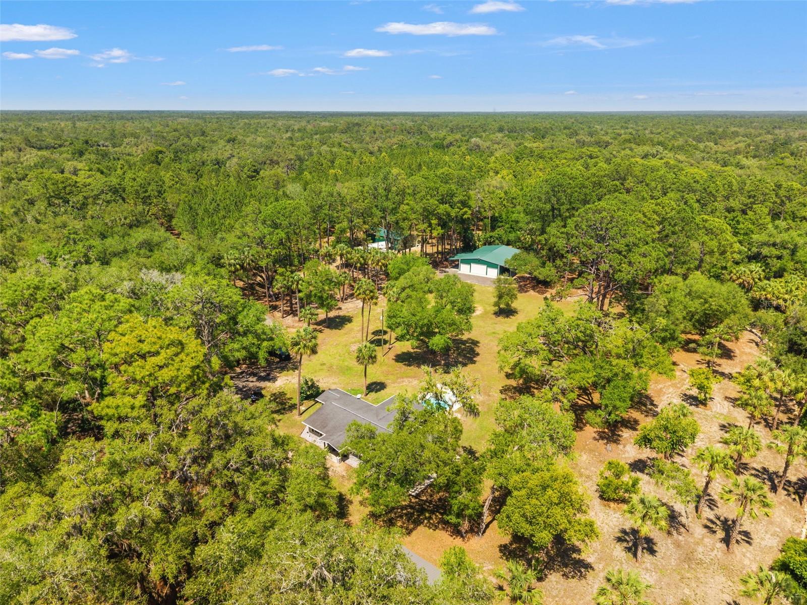 What’s behind the gate?? Featuring a beautifully laid out pine tree farm equestrian estate. Bring your animals! Some properties check boxes. This one rewrites the list entirely. Tucked behind electric entrance gates on 31.91 private acres, this estate has been obsessively built out from the ground up. Nearly every structure on the property is 2020 or newer, and it shows in every detail. The pine tree farm sets the mood the moment you arrive, with scenic views right from the beginning. Stepping into the home, you’ll see that it was fully renovated in 2021, with no stone left unturned. Three bedrooms, two and a half baths, leather granite countertops, bamboo flooring, tankless hot water heater, and a generator hookup already wired and waiting. The roof and A/C were both replaced in 2020. Out back, the heated saltwater pool with a built in hot tub (2021) showcases scenic views of a remarkable estate. Enjoy beautiful nights in the backyard with the pergola and backyard built for entertaining. The land is where this property truly separates itself. Eight paddocks, all with water. A 40x100 barn with six stalls, water, and 100-amp service. Two additional stables. A chicken coop. A separately deeded 1.37-acre bull pen. Orange trees. Pear trees. The entire property is fenced and cross fenced. This isn’t just acreage, this property makes you feel like you’re in a whole different world. The separate buildings alone would sell most properties. A 40x60 workshop with full spray foam insulation, air conditioning, 100 amp service, and water. An oversized two car garage built in 2023 with the same specs and quality. A 40x60 RV shed with 50-amp service and water. A 60x30 structure near the mobile with RV hookups. A feed shed with power and water. Every single one of them has power doors. The mobile home has been converted into an additional workshop, but can be easily converted back for multi-generational living. The workshop features room for multiple lifts, not to mention the huge entertainment space in the back, already built out and perfect for entertaining, to just getting away. This is the kind of property that takes years to put together. Someone already did that work for you. Stepping into this property doesn’t just make you feel like you’re looking at your next home, it makes you feel like you’re in a movie, giving you the perfect canvas to write your story. A full security system keeps watch over all of it for extra peace of mind. The location is perfect, tucked away with your own retreat, but still close enough to all you can ever need. Shops, hospitals, dining, and jump right onto the Suncoast in only a few minutes. Homes like this don’t come across too often, call quick before you miss it!