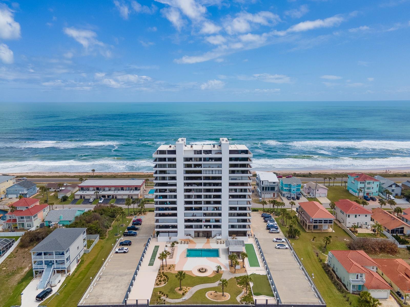 RARE OCEAN BLOCK CONDO OFFERING BOTH OCEAN & INTRACOASTAL VIEWS! The Iconic Aliki Gold Coast Condominium, where you will enjoy morning ocean sunrises and evening river sunsets from 25’ covered balconies on both the east and west facing elevations. The beach is just steps away for fishing and surfing, or just simply lounge to the sound of the ocean waves crashing and watch the pelicans flying in formation. Every winter there are ocean sightings of Atlantic Right Whales, as Flagler Beach is on the migration path for these rare creatures who seek warmer waters. Flagler Beach is truly a one-of-a-kind place in many other ways. This old school beach town is starting to gain a sophisticated vibe, yet the lifestyle here remains as casual as swimsuits and flip flops, with friendly neighbors riding golf carts and bicycles all over the island to enjoy unique eateries, shops and outdoor activities. The Pier (re-build set for completion in December) at the beach boardwalk and the new Compass Margaritaville Hotel anchors Veteran’s Park, where you will find a Saturday Farmer’s Market and the setting for countless local events. Flagler Beachside retains its charm by not allowing chain restaurants and stores. The iconic Aliki is set apart as the only mid-rise building here on the Island, with maximum 3 story height restrictions in place since it was built. Step inside to be greeted by an elegant lobby with sliding glass doors show casing the beautiful pool and other amenities riverside. On the 2nd floor, a landing opens to this home, featuring an open plan living and dining space. A soothing color palette of creamy painted walls and sand tones in the porcelain tile plank flooring set the stage for the magnificent ocean and river views. Step out onto the covered balcony to feel the ocean breezes and smell the salt air. The kitchen adds contrast and warmth with wood cabinetry and granite-look countertops. Both the primary and second bedroom are generously sized and share a covered balcony overlooking the Intracoastal Waterway. Practical touches—storm shutters on all sliding doors, window treatments, an interior laundry room, plus reserved garage parking space and private storage unit are included. There is an abundance of parking for guests as well. The Aliki sets the standard for coastal living with an impressive lineup of amenities: a refreshing pool, shaded outdoor kitchen with barbecue grills, shuffleboard and bocce courts, a putting green and an inviting social room ideal for gatherings. And best of all, direct beach access! The monthly HOA fees include water, sewer, trash, internet, cable, building insurance, exterior maintenance and management. Built with robust concrete construction and maintained to exceptional standards, the building has passed all mandated inspections and is supported by a current milestone report, giving peace of mind with long term stability. Whether you’re looking for a second vacation style home, to invest, or make it your permanent residence, you will be able to enjoy a truly turn-key experience here. Flagler Beach is just 3 miles from I-95 and ideally situated between historic St Augustine and world-famous Daytona Beach.