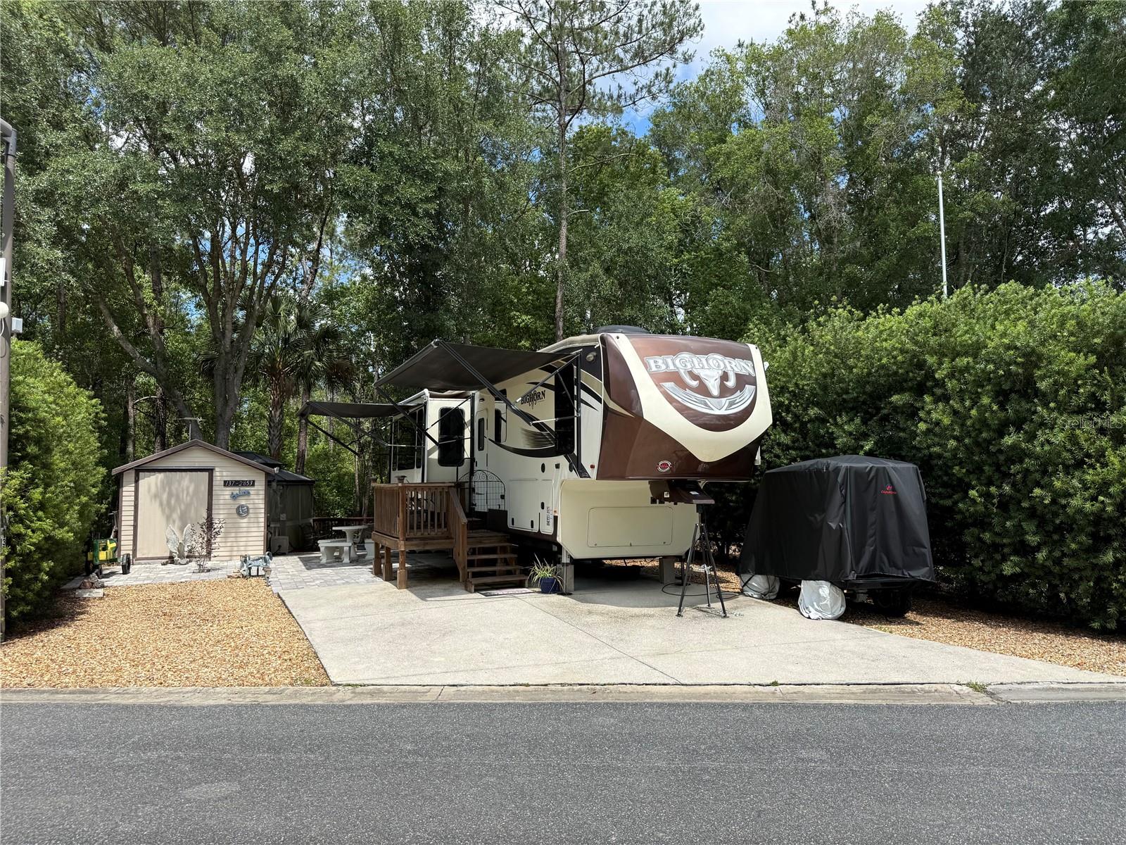 Welcome to an incredible opportunity in the highly desirable 55+ waterfront community of Wilderness RV Resort, where peaceful nature, resort-style amenities, and true Old Florida charm come together beautifully. Included with the sale is a beautifully maintained Heartland Bighorn 3575EL fifth wheel RV, allowing you to immediately begin enjoying this extraordinary retreat from day one. This deeded RV lot offers one of the most private and serene settings currently available in the community, backing directly to untouched wooded land that creates the feeling of camping deep within the breathtaking Ocala National Forest. Surrounded by nature and abundant wildlife, this property provides an atmosphere that is incredibly difficult to find. The outdoor living space has been thoughtfully designed for relaxation and entertaining, featuring a beautiful decorative paver firepit perfect for cool evenings under the stars, a spacious wood deck overlooking the wooded backdrop, and a gazebo complete with TV where you can unwind, watch the game, or simply enjoy peaceful evenings outdoors. A storage shed with electric adds convenience and functionality for tools, golf cart accessories, and additional storage. This is currently the only available lot on the wooded side of the resort, making it an exceptionally rare opportunity for buyers seeking maximum privacy and tranquility. Residents of Wilderness RV Resort enjoy an impressive list of amenities including a sparkling swimming pool, clubhouse, pavilion, fitness center with both free weights and exercise machines, dry and steam saunas, laundry facilities, and scenic golf cart trails that wind along the beautiful Ocklawaha River offering stunning natural views and peaceful waterfront scenery. Just outside the gated entrance you will find a popular local diner known for fantastic breakfast and lunch along with the famous MoonPie General Store filled with nostalgic charm and unique treats. Nearby historic downtown Ocala and the vibrant Ocala Square district provide endless entertainment, dining, and nightlife including the world’s largest candy store, the famous Brick City Southern Kitchen & Whiskey Bar with outstanding BBQ and a pool hall featuring a full liquor bar upstairs, the beautifully restored Marion Theatre offering movies, events, and cocktails, elegant dining at Ivy on the Square, Cajun favorites at Harry's Seafood Bar & Grille, and exceptional steaks at Mark's Prime Steakhouse. Whether you are searching for a winter getaway, full-time RV lifestyle, or a peaceful retreat immersed in nature, this extraordinary property offers a rare combination of privacy, amenities, and location that truly captures the very best of Florida resort living.