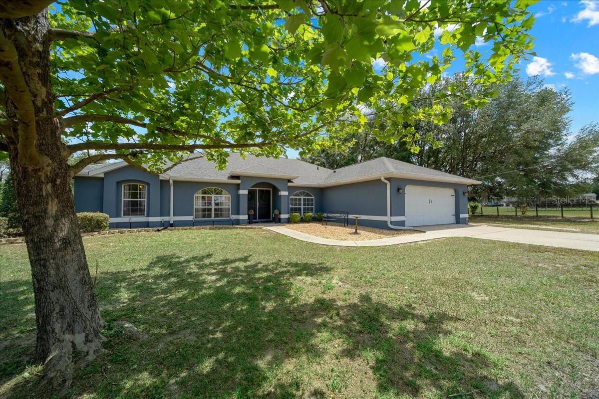Tucked away on a quiet dead end street, this beautifully maintained 3 bedroom, 2 bath home with a 2 car garage and a versatile office/bonus room offers 2,208 sq. ft. of living space on 4.97 private acres. With water access behind home, it perfectly blends comfort, nature, and convenience in one exceptional property. Ideally located near the water, you’re directly across from Bowers Lake and just 2.9 miles from Carney Island on Lake Weir, offering quick access to some of Central Florida’s best fishing, boating, and kayaking. From the moment you step inside, you’re greeted with breathtaking views of your private backyard, setting the tone for the peaceful lifestyle this home provides. Vaulted ceilings elevate the main living space, where you’ll find a spacious living room highlighted by a stunning wood accent wall and a cozy electric fireplace, perfect for relaxing evenings at home. The heart of the home is the oversized kitchen, thoughtfully designed with abundant cabinet and counter space, granite countertops, and an eat in area, making it ideal for entertaining family and friends. Expansive primary suite is a true retreat, featuring a generous walk in closet and a spa like en suite bathroom complete with dual vanities, a Jacuzzi tub, and a large tiled walk in shower. On the opposite side of the home, two well sized guest bedrooms are paired with a centrally located guest bathroom, offering privacy for guests or family. Through the sliding glass doors, enjoy an oversized screened in porch with peaceful backyard views and natural water behind the home. Outside, evenings are perfect around the fire pit in a serene backyard featuring two sheds for storage, tools, or hobbies. A true nature lover’s setting, with sandhill cranes and local wildlife frequently passing through, creating a peaceful and picturesque atmosphere year round. Additional highlights include a fully fenced yard, perfect for pets, gardening, or simply enjoying your space in privacy. Recent upgrades provide peace of mind, including a New roof 2021, New High Efficiency HVAC system 2025, and a 1 year home warranty offered at closing. If you’ve been searching for privacy, space, and proximity to beautiful Florida waterways, this property delivers it all. Schedule your private showing today and experience the lifestyle this home has to offer!