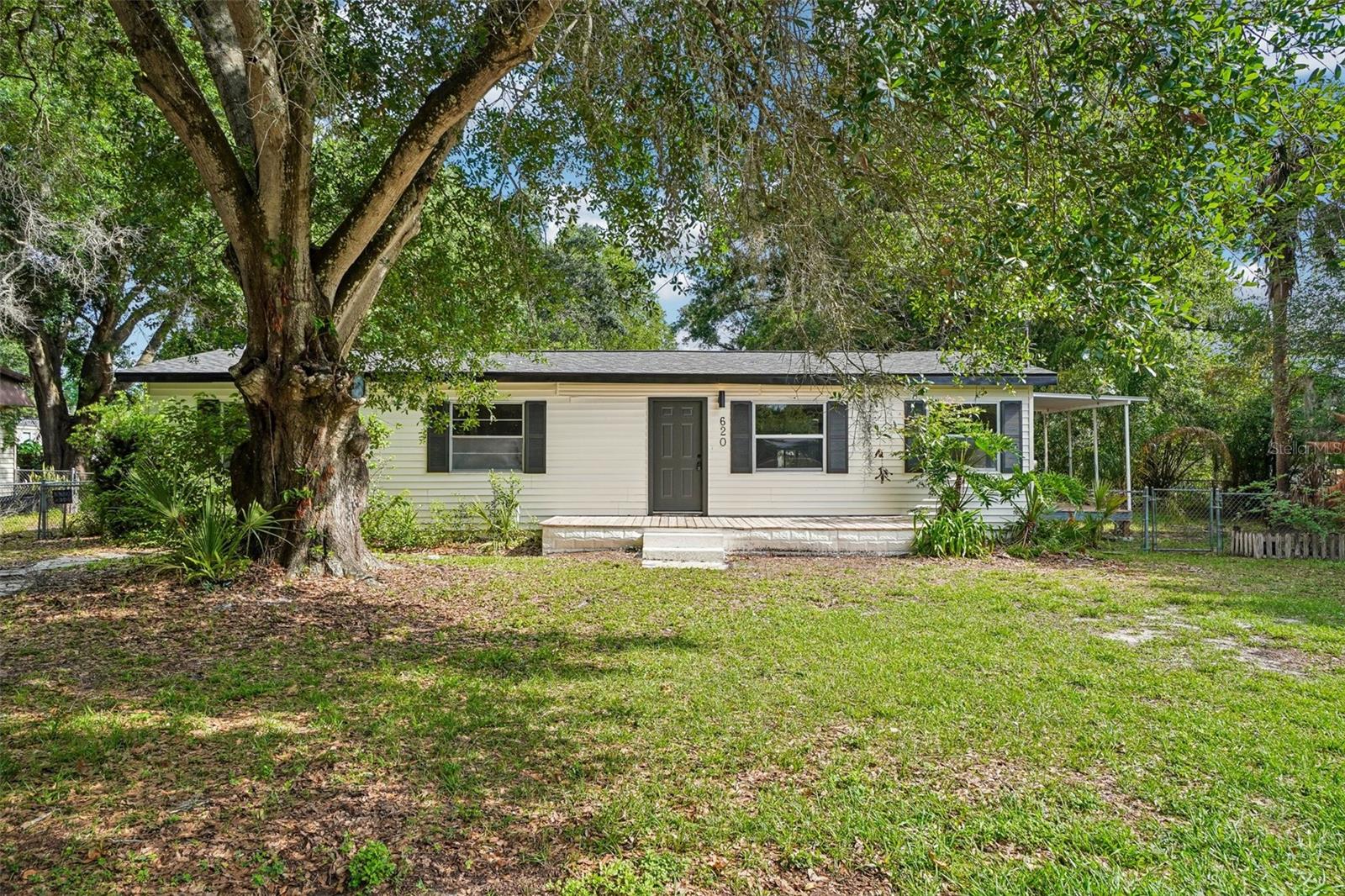 Welcome to this charming 3-bedroom, 2-bathroom single-family home located at 620 2nd St in the heart of Polk City, FL. Offering 1,012 sq. ft. of living space, this residence boasts a bright and open-concept layout with stylish light wood-tone LVP flooring, a neutral color palette, and abundant natural light. The beautifully appointed kitchen is equipped with crisp white shaker cabinets, sleek black hardware, modern white countertops, and a striking black faucet, flowing seamlessly into a spacious living and dining area perfect for everyday living and entertaining guests. A versatile enclosed sunroom/flex space with plush carpeting offers a cozy indoor retreat, while the dedicated utility room provides convenient laundry hookups. Step outside onto the inviting wooden front deck to enjoy the Florida breeze, or take advantage of the generous lot size with mature trees and plenty of outdoor space. Perfectly situated close to local schools, parks, and offering easy access to major routes between Lakeland and Orlando, this move-in-ready home is ready for its next chapter.