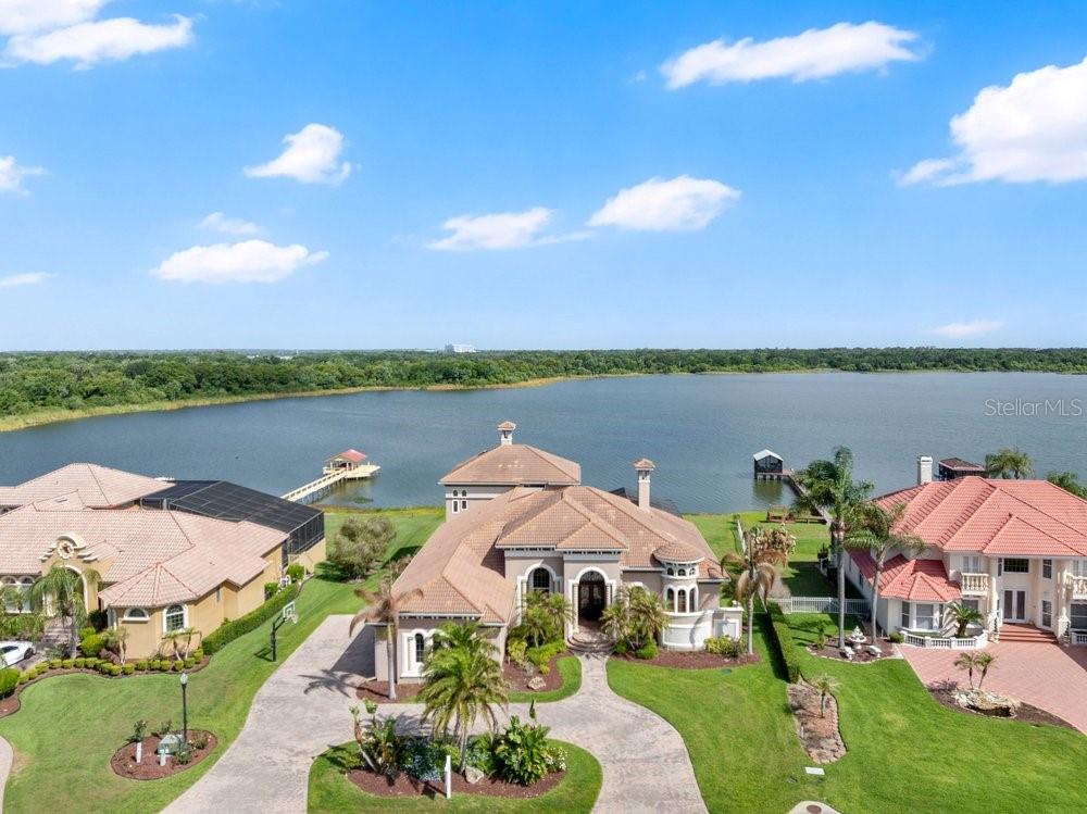 The epitome of Florida lakefront living, this six-bedroom, five-and-a-half-bathroom estate in the gated Highlands by the Lake community offers a rare synthesis of architectural grandeur and meticulous modern stewardship. Situated on nearly an acre with direct frontage on Banana Lake, the residence is introduced by an arrival sequence featuring iron Cantera doors that open to soaring 13-to-16-foot ceilings and a magnificent domed dining room. The interior is defined by a sophistication, where pocketing sliding doors and tinted rear windows dissolve the boundaries between the refined living spaces and the verdent lakeside setting. The home’s infrastructure has been rigorously modernized, featuring a 5-HP Trane HVAC system (2025), a secondary upstairs unit with a dedicated dehumidifier (2026), and two new tankless water heaters (2025). New, high-efficiency Pella windows constitute all but 6 windows throughout the home, complemented by whole-home surge protection, whole home Mulligan water filtration system, and an ADT security array consisting of 14 perimeter cameras.
The culinary center is a testament to functional luxury, equipped with a gas cooktop, custom all-wood cabinetry, a new garbage disposal (2024), and a stainless-steel utility suite. While the kitchen’s digital hub and the home’s televisions do not convey, the residence is a technological fortress, wired for 7G connectivity with an integrated Sonos surround-sound system and a theater room featuring SONY cinema equipment. The primary wing has been thoughtfully updated with 2023 luxury vinyl flooring, electric privacy curtains, and a primary bath featuring a bidet and "Closets by Design" cabinetry. Additional interior highlights include a Jack-and-Jill suite completely renovated in 2024, new light fixtures throughout, and three distinct garage bays featuring insulated doors, epoxy flooring, a Tesla charger, and significant integrated storage.
Outdoor living is elevated by a saltwater Pentair pool—equipped with a 2024 pump and auto-refill system—housed within a cage featuring 2024 lighting and a 2025 screen replacement. The grounds are illuminated by architectural lighting and protected by a "Bug Slayer" system and a transferable septic maintenance subscription. A Trex elevated party deck leads to the water's edge, where a recently improved dock and electric lift provide seamless access to Banana Lake. Residents of this exclusive enclave enjoy not only profound privacy but also a suite of community amenities, including a clubhouse, pool, pickleball, and tennis courts, all positioned strategically within the I-4 corridor between Tampa and Orlando.The current mortgage is a VA assumable loan at a 5%interest rate. Please inquire for more information.