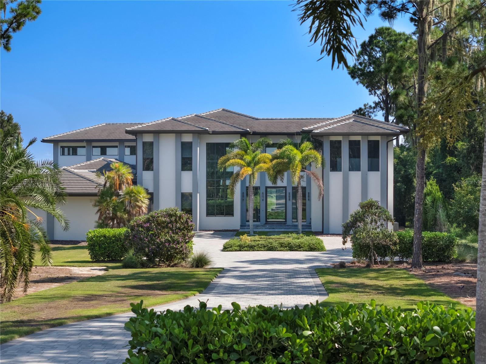 Welcome to the ONLY move in ready fully custom home with an opportunity for a private boat dock offering  LONG RANGE VIEWS on Lake Apopka. This immaculate showcase home in the highly sought after gated community of Bella Collina offers panoramic views from the moment you step inside. Soaring 24 ft ceilings with sleek lines compliment the decor and modern design of the home. The abundance of large windows and 10 ft sliding doors allow for plenty of natural light from every angle. A chef’s kitchen boasts a hidden walk-in pantry, Sub Zero fridge with matching cabinet front panels, Wolf induction cook top with hood, wolf drawer microwave. The large island overlooks the great room, adjacent to the dining area and wine wall, all offering spectacular views of the custom designed pool and lake Apopka. As you enter the primary suite you can’t help but notice the soaring ceilings, 10 ft sliding glass doors with blackout drapes, and the tremendously large platform bed. The gorgeous ensuite bathroom presents a free-standing soaking tub, large walk-in shower with multiple jets, rain shower head and remote controls, separate vanities, additional make up vanity, along with his and hers toilets. Passing through the bathroom you enter the incredible double story closet with waterfall island illuminated by an elegant chandelier in the center which drops down from the second floor. A staircase from the two story closet opens to the second floor loft/media area that can double as a theatre room.   Four additional oversized bedrooms have ensuite bathrooms, walk in showers and remote-controlled window shades. Additional features are an air-conditioned basketball court, large home gym with weight equipment and sauna. The backyard oasis with outdoor kitchen and custom pool with spa are perfect for taking in the peaceful views. The owner has installed a mosquito misting system in the backyard. There is plenty of space perfect for entertaining family and friends. The Savant smart home technology with iPad/cell integration offers full home automation including six interior/ten exterior cameras with voice recording, sound system in every room, remote control blinds, door locks, air conditioning, and complete home lighting with customizable mood settings. Additional features are an air-conditioned basketball court, large home gym with weight equipment and sauna. The Club at Bella Collin offers year-round social and culinary events for all ages. Enjoy a game of pickle ball, a round of golf or a challenging tennis march with neighbors. Bella Collina offers unparalleled amenities including the Nick Faldo designed 18-hole golf course, outdoor pool complex, multiple dining venues and fitness center offering 20 complimentary fitness classes a week This custom masterpiece must be seen to truly appreciate its beauty and elegance. Call to today to set a private viewing appoint and to learn more about the lifestyle offered in Bella Collina.