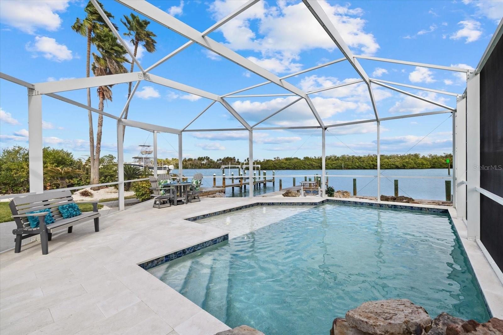 HURRICANE PROTECTION! PRIVATE BOAT RAMP! HEATED POOL! 611 S Casey Key Road is a true waterfront sanctuary where every detail is designed to celebrate life on the Intracoastal, with effortless and immediate access to the Gulf. Recent updates provide both luxury and peace of mind, including two HVAC systems (2021 and 2025), new heated saltwater pool and pool cage (2022), garage doors (2019) as well as IMPACT GLASS windows. Set on approximately 1/3 of an acre on iconic Casey Key, this elevated coastal residence offers a front-row seat to sparkling water views from every bedroom, complemented by gentle sea breezes and unforgettable sunsets. The main living area is thoughtfully positioned on the second floor, where a wall of windows frames the ever-changing blues of the Intracoastal Waterway. An open and airy great room invites you to linger, whether hosting gatherings or enjoying quiet mornings as dolphins play. The same continuous tile flooring throughout enhances the clean, coastal aesthetic while keeping the focus on the views beyond. The kitchen is both functional and inspiring, perfectly open to the great room and oriented toward the water, featuring quartz countertops that extend into all bathrooms for a cohesive, elevated finish, making entertaining and everyday living equally refined. The primary suite is spacious and tranquil, offering water views that greet you at sunrise, a walk-in closet, and an en-suite bath with a tiled shower and glass doors. A second en-suite bedroom also features a walk-in closet, a beautifully appointed bath, and equally stunning water views, ideal for guests who appreciate both comfort and privacy. A third bedroom, also enjoying water views, is served by a full bathroom with a tub/shower combination. A versatile bonus room with barn doors and a closet easily functions as a fourth bedroom, home office, or sitting room to catch a glimpse of the Gulf. A second-floor laundry adds everyday convenience. On the ground level, a generous two-car garage is paired with a dedicated workshop; perfect for boating gear, paddleboards, kayaks, or creative projects. This unfinished non-conforming space offers endless possibilities. Outdoors, the property transforms into a private waterfront resort. Relax beside the HEATED saltwater pool (2022) surrounded by a travertine tile pool deck, step onto your dock to cast a line, or launch directly from your PRIVATE BOAT RAMP and cruise to the Gulf with NO BRIDGES, a rare and invaluable luxury for avid boaters. Waterfront dining, sandbars, and open-water adventures are just moments away. When the mood shifts to beach time, enjoy the privilege of deeded Gulf beach access, only steps from the sand, turquoise waters and gorgeous sunsets. With HURRICANE IMPACT GLASS throughout and a coveted location near the public beaches and charm of Nokomis and a short drive to downtown Venice and the arts and culture of Sarasota, this home delivers an unparalleled blend of privacy, elegance, and coastal freedom. This is not simply a residence—it is a lifestyle defined by water, light, and the rare joy of living near to where the Intracoastal meets the Gulf.