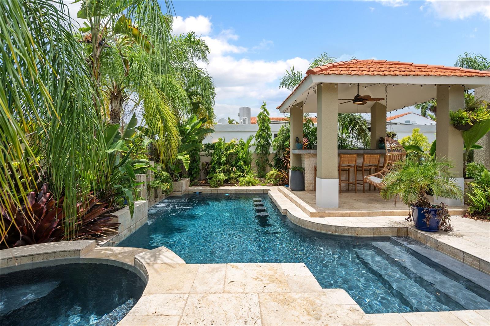 Completely remodeled Villa Carbia offering one of the most unique settings in Sabanera Dorado. Surrounded by mature tropical landscaping, this exceptional home feels like a private nature retreat where lush greenery creates a peaceful, almost jungle-like atmosphere rarely found within a community. Whether relaxing by the heated saltwater pool, soaking in the hot tub, entertaining under the gazebo, or enjoying the covered terrace, every outdoor space feels immersed in nature. A separate side terrace, nestled among tropical landscaping and a mature mango tree already producing fruit, offers yet another peaceful place to unwind.
Inside, the home has been thoughtfully renovated from top to bottom with elegant marble floors throughout, beautifully redesigned bathrooms, and new windows that flood the interiors with natural light while framing the lush outdoor scenery. The dramatic living room features soaring cathedral ceilings with exposed wood beams, creating a warm and inviting atmosphere, while the spacious primary suite offers its own cathedral ceiling and wood beam accents, making it a true retreat. Nature-inspired finishes and thoughtfully curated décor create a seamless connection between the indoor and outdoor living spaces.
Designed for both comfort and efficiency, the home includes a 54-panel solar system producing approximately 24 kW, four Tesla Powerwall batteries, a heated saltwater pool with a new pump and filtration system, water cistern, and water softener. Beautifully renovated and completely move-in ready, this is a home that offers not only exceptional upgrades, but a lifestyle where comfort, privacy, and nature come together in perfect harmony.