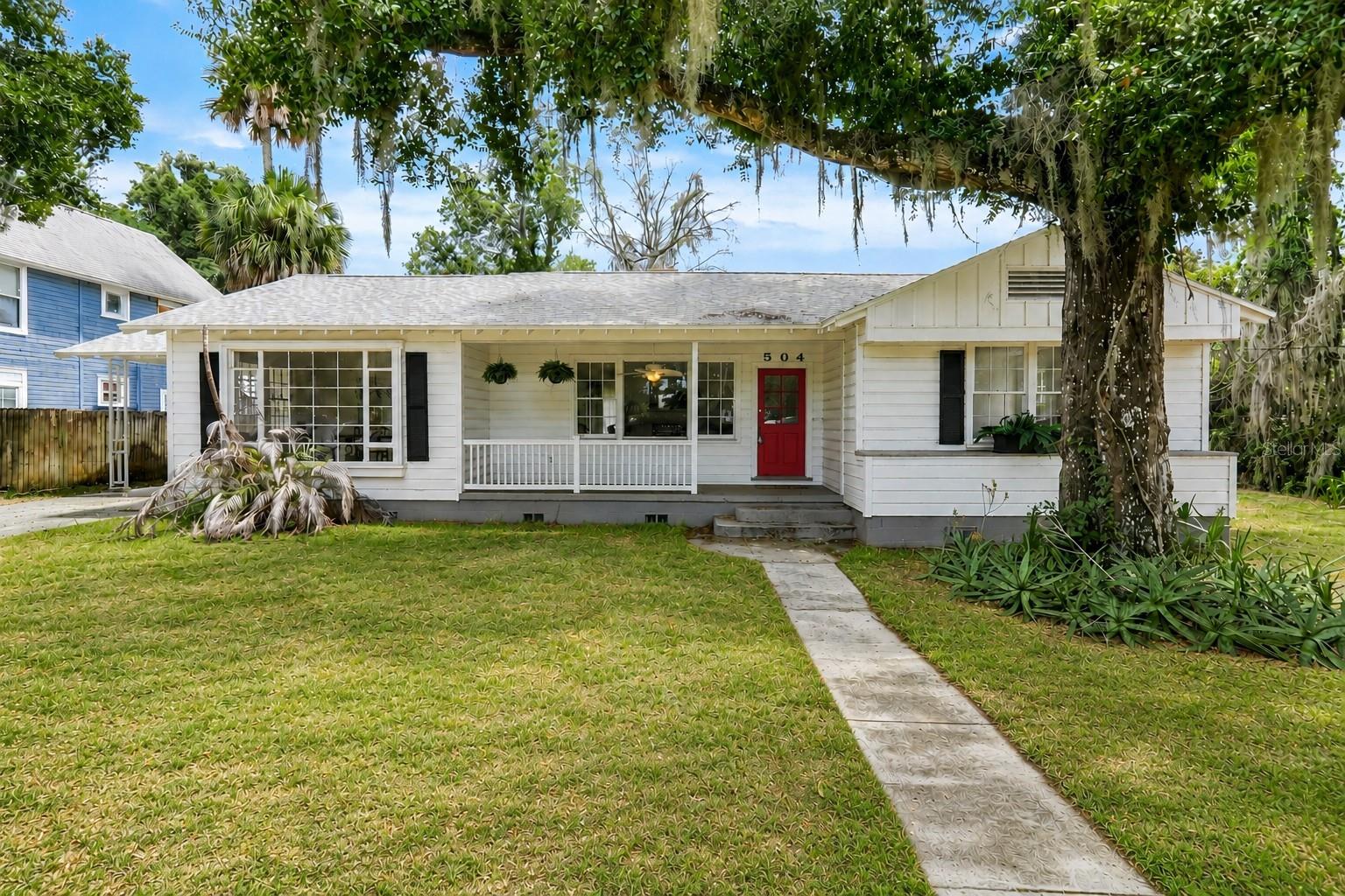 Welcome to 504 E Citrus Ave, where timeless Old Florida charm meets the heart of historic downtown Eustis! Nestled beneath beautiful shade trees, this one-of-a-kind home welcomes you with a spacious front porch that is perfect for rocking chairs, morning coffee, and relaxing evenings.Inside, you’ll find a truly unique floor plan filled with character and vintage charm. The oversized living room centers around a stunning fireplace featuring classic black vintage tile and an elegant mantle straight out of a Southern Living magazine. A large formal dining room offers abundant natural light through expansive windows and connects to the charming vintage kitchen through an original swinging door. The kitchen retains its classic appeal with original white cabinetry and glass-front doors that add warmth and personality. Just off the living room is a lovely Florida room, creating the perfect flex space for reading, entertaining, or enjoying peaceful backyard views. The home also features two oversized bedrooms and more than 1,600 square feet of living space. Situated on an impressive nearly 1/3-acre lot measuring approximately 100 feet wide by 120 feet deep, there is plenty of room to enjoy outdoor living, gardening, or future possibilities — all with NO HOA!Located in the historic downtown Eustis area, you can enjoy walking to local shops, restaurants, waterfront events, and the famous Eustis First Fridays. With exciting growth and revitalization happening throughout downtown Eustis, this is an incredible opportunity to own a distinctive home full of charm, history, and potential.Come experience the character and warmth of this special property — homes like this rarely come available!