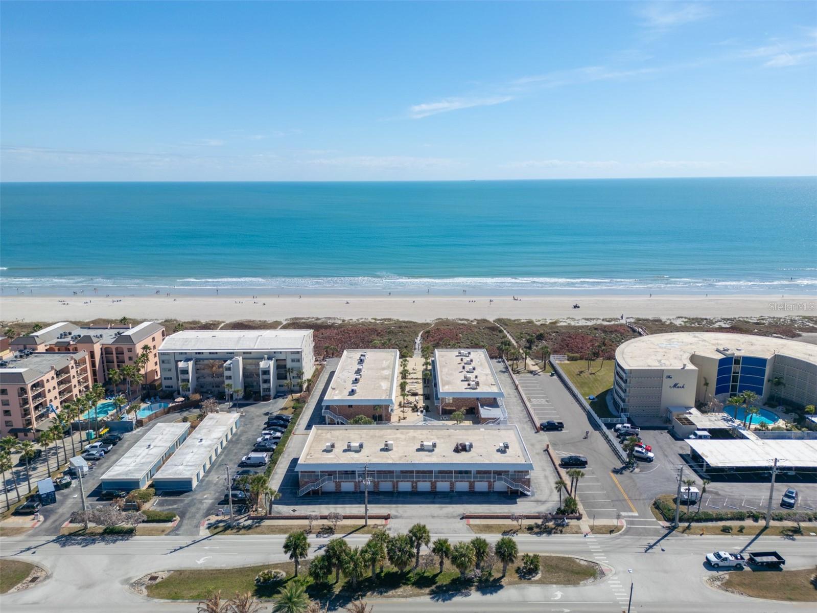 Ocean views greet you the moment you enter this fully furnished 2-bed, 2-bath end unit on the 2nd floor, only steps from the sand! The open floor plan features tile floors in main living areas, an updated kitchen with granite counters, stainless appliances and breakfast bar. From the light and bright living room, sliders lead to an expansive balcony with new patio furniture. The carpeted primary bedroom offers a private en suite bath. Both bathrooms were fully renovated in 2025 with new fixtures, tiled showers, and wood-look laminate flooring. A private garage sits just below the unit. Additional highlights include in-unit washer/dryer and a renovated pool, car wash, clubhouse and beach access. Located just half a mile from the Cocoa Beach Pier, 3 miles to downtown Cocoa Beach, 3.5 miles to Port Canaveral's dining and cruise terminal. Whether a beachside retreat or savvy investment, the 3-month minimum makes this turnkey gem a rare find. Enjoy oceanfront living at Oceanside Villas!