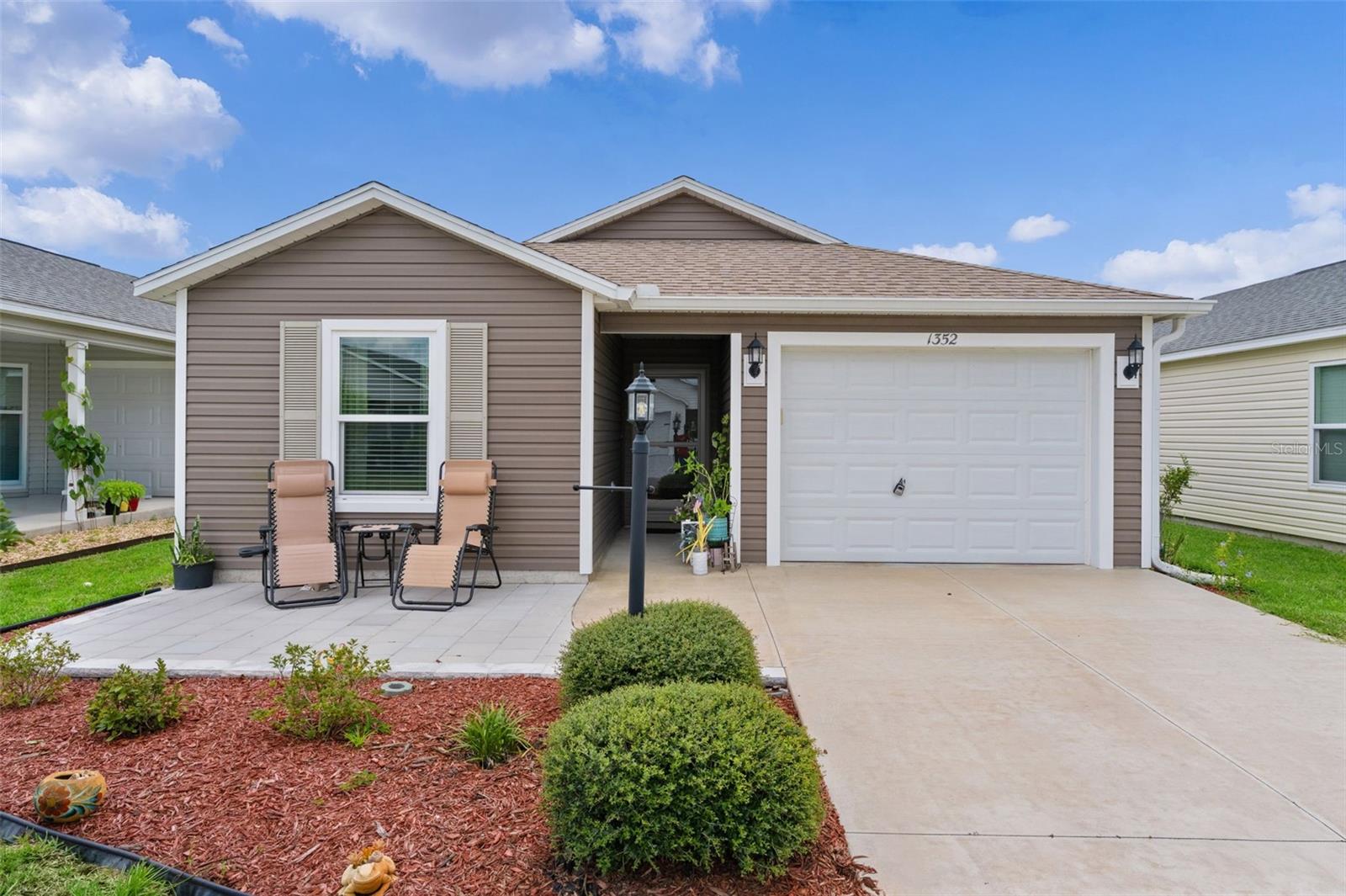 ~2020 ROOF, HVAC, and HOT WATER HEATER~ ~TANDEM GOLF CART GARAGE~ Welcome to this beautifully maintained RETREAT model in the desirable Village of HAWKINS, offering modern finishes, low-maintenance living, and an ideal location close to all the amenities of The Villages. Built in 2020, this charming home combines contemporary style with thoughtful design, making it perfect as a full-time residence, seasonal getaway, or investment property. A welcoming PAVER FRONT PATIO provides the perfect spot to enjoy your morning coffee or greet neighbors. Step inside to an OPEN FLOOR PLAN highlighted by VAULTED CEILINGS and attractive vinyl flooring throughout the main living areas, with plush carpet in the bedrooms. The spacious living room features a ceiling fan and flows seamlessly into the dining area and kitchen, creating a bright and inviting space for entertaining. The kitchen is designed for both style and function, featuring HI-DEF countertops, STAINLESS STEEL appliances, convenient CLOSET PANTRY, and ample cabinet space. The adjacent dining area offers a vaulted ceiling that enhances the open and airy feel. The private primary suite includes carpet, high ceiling, ceiling fan, & generous WALK-IN CLOSET. Note the stylish barn door which allows access to the convenient stacked full-size washer and dryer. The ensuite bath features custom glass shower sliding doors and HI-DEF countertops. The guest bedroom is equally inviting with carpet, ceiling fan, high ceiling, and built-in closet. The guest bath includes a tub/shower combination and matching HI-DEF countertops.  The tandem golf cart-forward garage offers excellent space for both your vehicle and golf cart. This move-in-ready Retreat model offers modern construction, quality finishes, and the easy Florida lifestyle you've been looking for. Located conveniently close to Magnolia Plaza, Brownwood Paddock Square, Sawgrass Grove, Edna's on The Green, while not far from Eastport. Golf is nearby at Southern Oaks, Lowlands, Mickey Lee, and Marsh View golf courses. Rec centers include Hawkins, Aviary, Ezell, Everglades and Rohan.