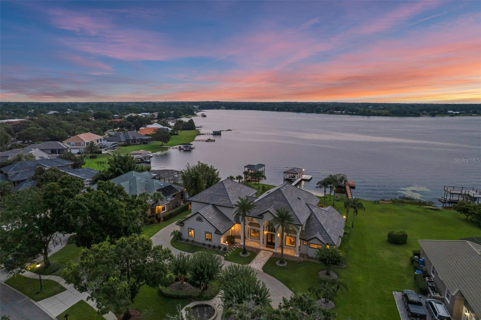 **Video tour and 3D floorplan experience available.** Indulge in ultimate luxury at this gated Lake Crescent retreat. Enjoy water-skiing on a private lake, fishing from your private boat dock, and marveling at rocket launches, stunning sunsets, and pontoon plane landings—all from your own backyard. Embrace Florida living with a heated saltwater pool and spa waterfall surrounded by a spacious travertine tile deck.  Relax on your private sandy beach or boat dock with a sundeck with electricity.  A stylish fountain, palm trees, and crepe myrtles adorn the circular driveway, leading to double front doors revealing soaring ceilings, travertine floors, a grand staircase, crown molding, and tray ceilings. The formal dining and living rooms feature a gas fireplace, stone accents, and a retractable TV, ideal for unforgettable gatherings. Glass folding doors open the wall completely to extend the living space to the pool area with a fire pit. The gourmet kitchen boasts the best view in town, custom cabinetry with pull-out drawers, ceiling-high storage with accent lights, tile backsplash, granite countertops, built-in refrigerator, full-size wine refrigerator, 6-burner gas range with pot filler, Dacor double oven, and warming drawer. The walk-in pantry and butler’s pantry/coffee bar offer custom cabinets, granite countertops, and a second full-size refrigerator. The wet island has ample seating, while the shaded lanai provides more dining space near the built-in gas grill, all with stunning pool and lake views.  The primary suite, located downstairs, features rich wood floors, glass doors leading to the patio, and two walk-in closets with custom cabinets. The spa-like primary bathroom includes a large shower, Jacuzzi tub, double vanities, granite counters, and a heated towel rack. Guests will enjoy a first-floor bedroom with a superb lake view and private access to the pool bath. There’s also a spacious in-law suite with a private entrance, walk-in closet, additional storage closet and private bath.  The main staircase leads to a library loft overlooking the living room plus three additional bedrooms: one with a private bath, and two sharing a Jack & Jill bath. Breathtaking balcony views are accessible from the loft or bedroom. Custom cabinets and granite throughout the wet areas in the home. A second staircase reveals a state-of-the-art theater with tiered seating, 4K projector, 4 TVs, wet bar, beverage fridge, and bar seating. TWO offices: one with a seating area, barn doors opening to a workspace, and new glass sliding doors overlooking Lake Crescent, plus a cozy second office that could be a workout or hobby room.  Additional features include a laundry room with custom cabinetry and granite countertops, and a 3-car garage with epoxy flooring, workbench alcove, built-in cabinets, overhead storage, and a pull-down screen door on the third bay. Recent upgrades: new tile roof on the house and boathouse (2025), new windows (2025), pool and spa resurfaced (2025), new paint inside and out (2025), tankless water heaters (2024), updated ACs (2018 and 2024), lighting, and re-decked dock with new electric (2024).  This neighborhood is minutes from downtown Windermere, Winter Garden, Disney World, and Dr. Phillips' fine dining. This is more than a home; it’s a lifestyle of unparalleled luxury and tranquility.