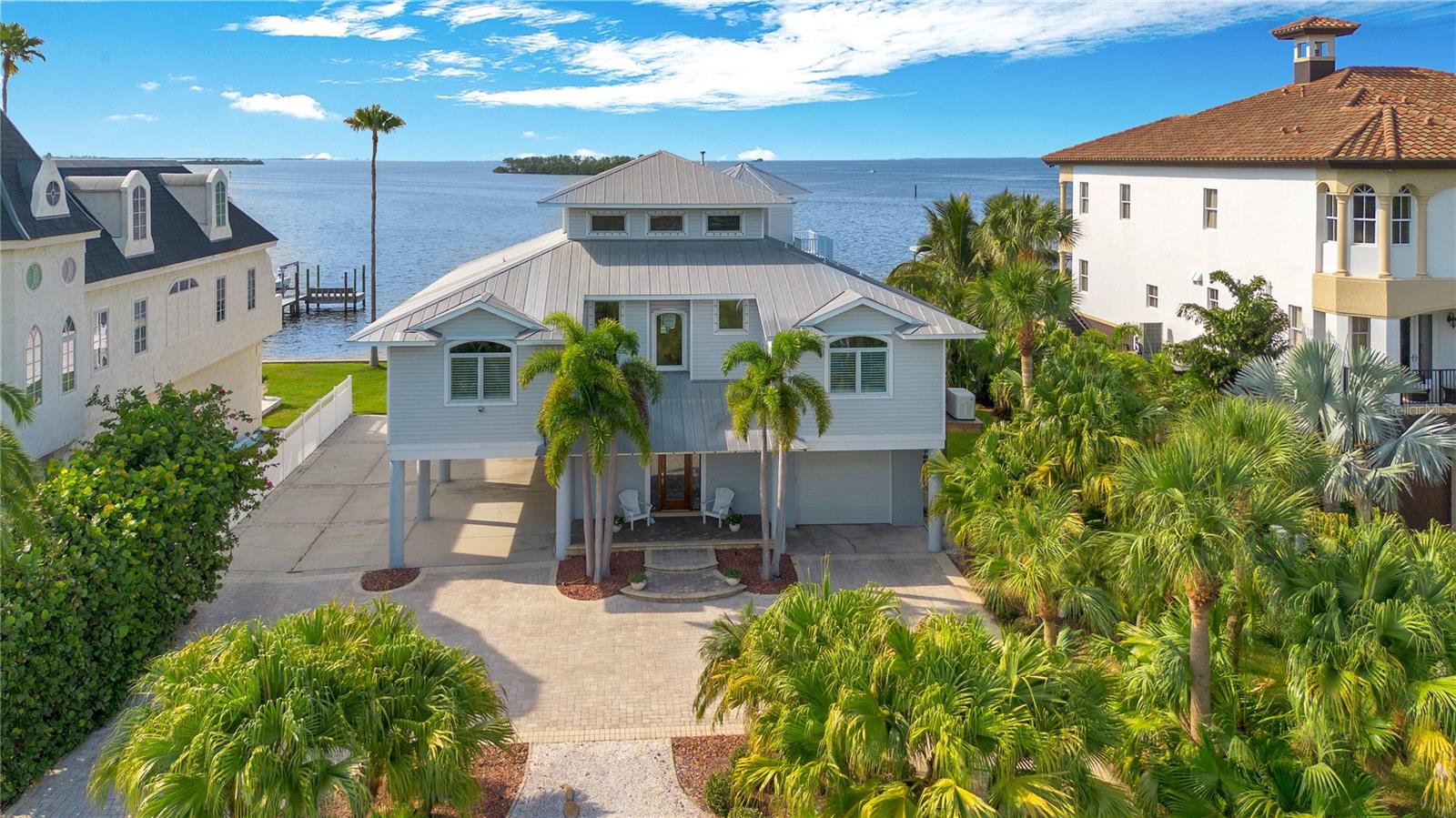 NO DAMAGE TO LIVING SPACE THROUGH BOTH HURRICANES! COVERED DOCK IN PERFECT SHAPE! Truly built correct! Come Discover one of the most extraordinary locations in North Pinellas County with this expansive double lot offering panoramic views of Honeymoon Island and Three Rooker Bar. Enjoy breathtaking sunsets each evening from the kitchen, living room, and master bedroom. The upper floor of this elevated home can serve as a separate in-law suite, complete with a living area, kitchenette, bedroom, bath, and air-conditioned storage.
 
Inside, the home is equipped with a central vacuum system, a Generac natural gas whole-house generator, and CCTV with monitors for enhanced security. The security alarm system and EV charging station add convenience and peace of mind. Elegant hardwood flooring throughout the home is complemented by a water softener for optimal water quality.
The property features an elevator providing access to all floors and includes custom storage cabinets in the three-car garage, with additional parking space available in the carport for three more vehicles.
  
Outside, the property boasts a covered boatlift and a 10’x 20’ dock. This property boasts a rare, separate front parcel that offers endless possibilities for customization and expansion. With direct open water access, this buildable lot currently features a private pickleball court, perfect for sports enthusiasts or those who love outdoor entertainment. Keep the existing pickleball court and add a guest house, creating the perfect retreat for visitors ! Alternatively, consider transforming the space with a large swimming pool, lush landscaping, or even a personal outdoor oasis. Whether you're looking to expand, entertain, or invest, this rare key lot sets this home apart from the rest, offering flexibility and unparalleled options. The location is ideal, with a short walk or boat ride to the marina for fuel, bait, and supplies, and close proximity to the Pinellas Trail, Honeymoon Island, Downtown Dunedin, and A-rated schools. Situated in the charming town of Ozona, this home is in the heart of Palm Harbor, surrounded by quaint shops and restaurants.
