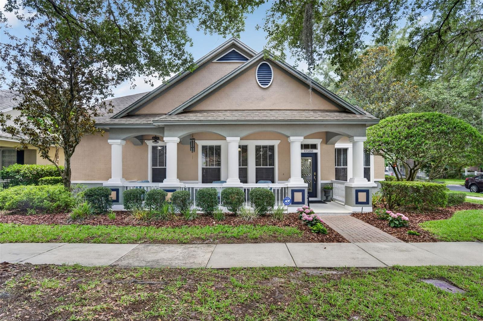 A rare first-time offering in the highly sought-after Lakes of Windermere, 12580 Cragside Lane is a meticulously maintained, original-owner residence with timeless appeal. Set on a desirable corner homesite, this thoughtfully designed single-story home offers 2,776 SF of living space w/ 4 bedrooms, 2 1/2 baths & a floor plan that gracefully balances formal entertaining w/ comfortable everyday living. A deep covered front porch stretches across the front elevation, creating a warm first impression. Inside, the foyer opens to elegant formal living & dining spaces highlighted by wood flooring, tall ceilings, extensive millwork, decorative niches & abundant natural light. A built-in dry bar w/ a wine refrigerator, additional cabinetry & serving space provides the perfect transition between the dining room & kitchen. At the center of the home, the kitchen opens seamlessly to the eat-in nook & family room, creating an easy flow for everyday living, casual dining & entertaining. The kitchen features a large island w/ seating, abundant wood cabinetry, generous granite countertops, stainless steel appliances & pantry. Large windows & glass doors frame views of the covered rear lanai and charming fenced backyard, where refreshed landscaping & new sod create an inviting setting for year-round outdoor living. A conveniently located powder bath, sizable indoor laundry room & separate storage closet complete the main living area. Privately positioned at the rear of the home, the primary suite serves as a quiet retreat featuring a soft entry, wood flooring, an elegant tray ceiling, private access to the lanai & an expansive walk-in closet. The spacious bath offers a garden tub, a separate glass-enclosed walk-in shower w/ neutral tile, an oversized real wood dual-sink vanity w/ extensive granite counter space, large mirrors & a private water closet. Three alternate bedrooms occupy their own wing at the front of the home, providing excellent separation for family members or guests. The secondary bathroom features a long granite-topped vanity w/ dual hammered copper sinks & a private, combined water closet with tub/shower area. Additional improvements include a recently replaced Carrier HVAC air handler (2024), water heater (2020), Kinetico water softener, some newer appliances including a front-loading Samsung Bespoke washer & dryer, and a new roof, which the seller intends to install prior to closing. Outside, mature landscaping, sidewalks & a quiet rear alleyway complement the desirable corner homesite, while a rear-entry, attached 2-car garage adds everyday convenience. Located outside a designated flood hazard area, the home is zoned for highly regarded A-rated schools, including Sunset Park Elementary, Horizon West Middle & Windermere High School. Residents of Lakes of Windermere enjoy beautifully maintained parks, playgrounds, tennis courts, a clubhouse, a community pool, sand volleyball courts, scenic ponds, a fishing pier, recreational fields & walking paths all just minutes from Walt Disney World, Horizon West, Winter Garden Village, exceptional shopping, dining & major roadways providing convenient access throughout Central Florida. Lovingly maintained by its original owner for more than two decades, this exceptional residence offers an increasingly rare opportunity to own a well-cared-for home with timeless appeal, an outstanding floor plan & an exceptional location in one of Windermere’s most established & desirable communities.