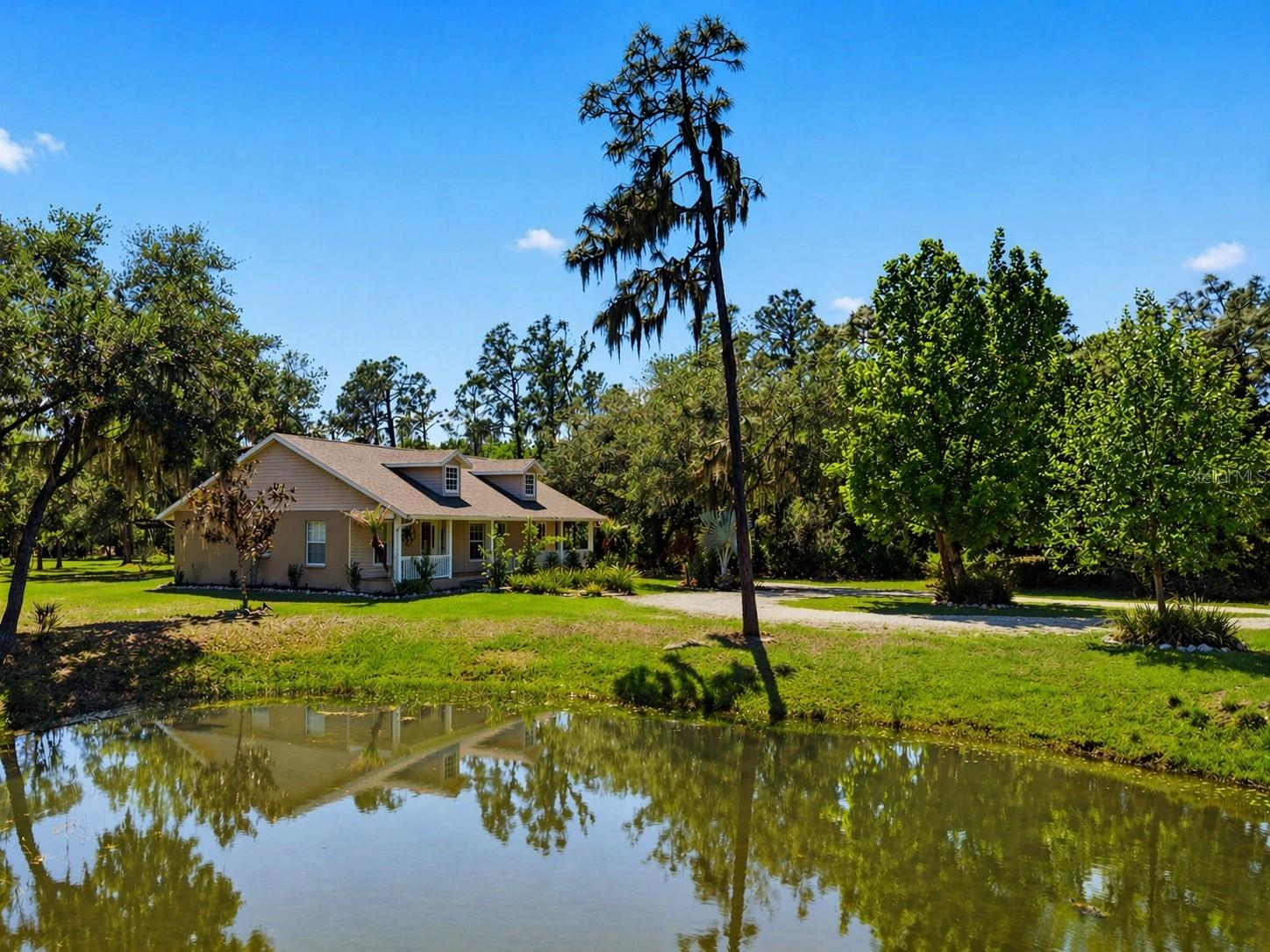 MAJOR PRICE IMPROVEMENT - Set on a private, pie-shaped 7.95-acre lot, In Winding Creek, that stretches deep into the lush wooded forest, this partially fenced estate offers a rare combination of usable land, natural beauty, and thoughtful improvements. The grounds feature a private fishable pond, expansive cleared areas for recreation, and wooded sections that create privacy, including a charming enclosed treehouse with deck. The home is complemented by a detached two-story carport offering two oversized covered parking area and two heated and cooled rooms (one upstairs and one downstairs, not included in the published sq/ft), ideal for an air-conditioned workshop, hobby space, or guest overflow. Additional exterior highlights include a well-maintained and covered well system with pump, bladder tank, and filtration, a huge circular driveway, irrigation system, and beautifully manicured front and rear lawns with lush landscaping. Inside, the open floorplan features vaulted ceilings throughout the main living areas, a spacious living room with a wood-burning fireplace, and a kitchen with stainless steel appliances, breakfast bar seating, and a large dining area. The home offers three bedrooms and two fully updated bathrooms, along with an inside laundry room complete with washer, dryer, second refrigerator, and side entry access. Flooring includes hardwood and tile throughout the main living areas, bathrooms, and primary suite, with wood laminate in the secondary bedrooms. Enjoy outdoor living year-round from the 12x24 covered and screened rear patio with double door access from both the living room and primary bedroom. With a new roof in 2024 and a property that balances open space and wooded privacy, this is a truly unique opportunity to own nearly 8 acres with exceptional features and flexibility.  Winding Creek is a private, nature-surrounded community featuring an equestrian center and expansive common areas ideal for walking, hiking, biking, and horseback riding, conveniently located approximately 20 minutes east of I-75 off SR 64.