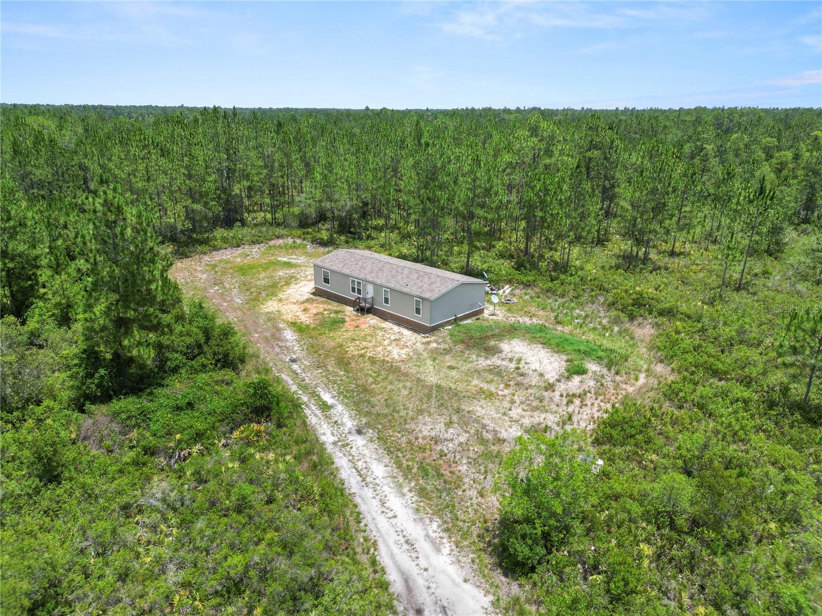 Escape to the peace and privacy of country living with this unique 18.75-acre family compound, offering the perfect blend of modern comfort and endless outdoor recreation. Built in 2023, the nearly new 1,680 sq. ft. manufactured home features 3 bedrooms, 2 bathrooms, an inviting open-concept kitchen, and a desirable split floor plan designed for comfortable everyday living. The spacious family room showcases built-in shelving with integrated wall storage, adding both style and functionality. The home is serviced by a private well and septic system, both installed new with the home's construction, while underground electric service enhances the property's clean appearance and reliability. The home also has a private road with a gate. 

Embrace the country lifestyle surrounded by Florida's natural beauty and abundant wildlife. Enjoy the privacy and space to explore your own land, observe native wildlife, forage for native plants (where appropriate), or create your own outdoor adventures. With nearly 19 acres, there's ample room to enjoy ATVs, UTVs, dirt bikes, or other off-road recreational vehicles on your own property, making this an ideal retreat for outdoor enthusiasts.

The sale includes two parcels totaling approximately 18.75 acres, creating exceptional flexibility for future expansion, a private retreat, or investment potential. Parcel 13-24-24-0001-000-19700 consists of approximately 10.72 acres, including a 1-acre homesite with the residence and approximately 9.72 acres of wetlands. Parcel 13-24-24-0001-000-31700 offers approximately 8.03 acres, including a 1-acre vacant residential homesite and approximately 7.03 acres of wetlands. Whether you're looking for a secluded homestead, a recreational getaway, or a peaceful place to enjoy nature, this one-of-a-kind property delivers privacy, modern conveniences, and room to live the Florida outdoor lifestyle you've been dreaming of.