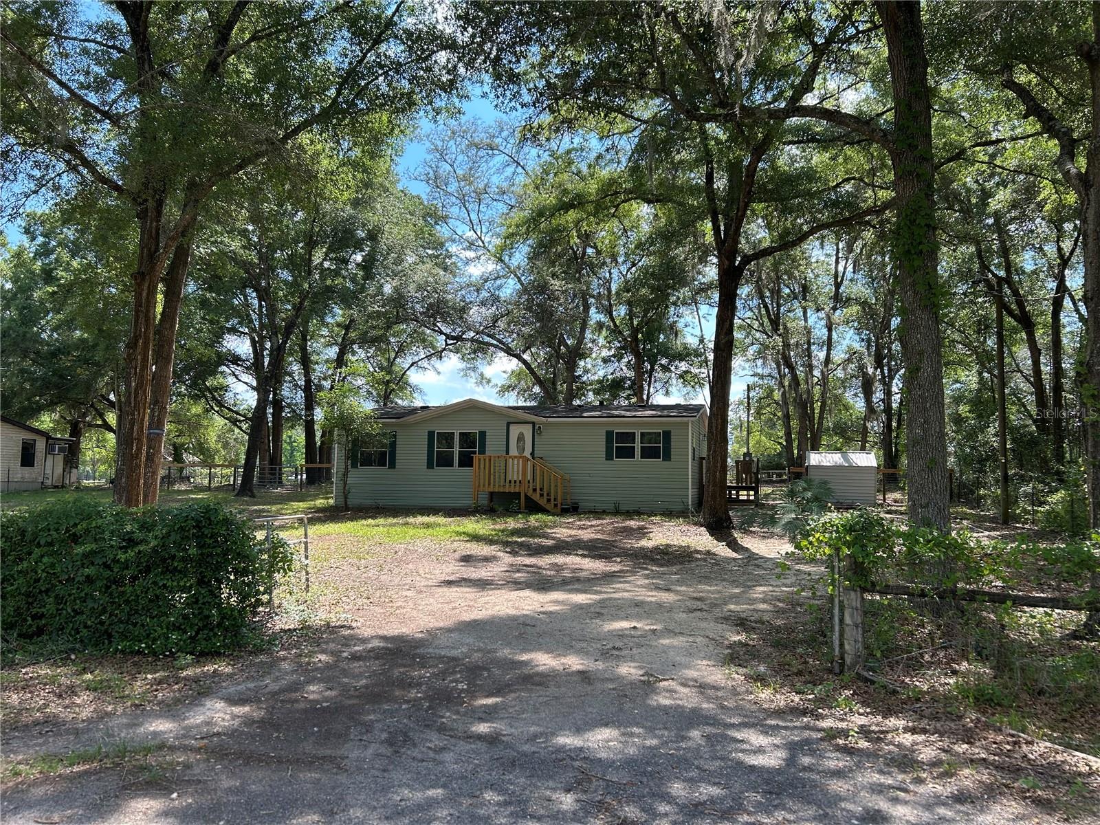 FULLY UPDATED COUNTRY CHARMER ON A SHADED HALF-ACRE! If you're looking for a move-in ready home with character, this beautifully remodeled 3BR/2BA double-wide delivers. Recent improvements include a new roof, fresh paint, luxury vinyl plank flooring, custom wood cabinetry, and a unique butcher block countertops, coffee and wine bar that adds warmth and personality. Situated beneath mature shade trees on a paved road and featuring fenced outdoor space for pets, gardening, or simply enjoying North Florida living, this property offers affordable country living without sacrificing comfort.