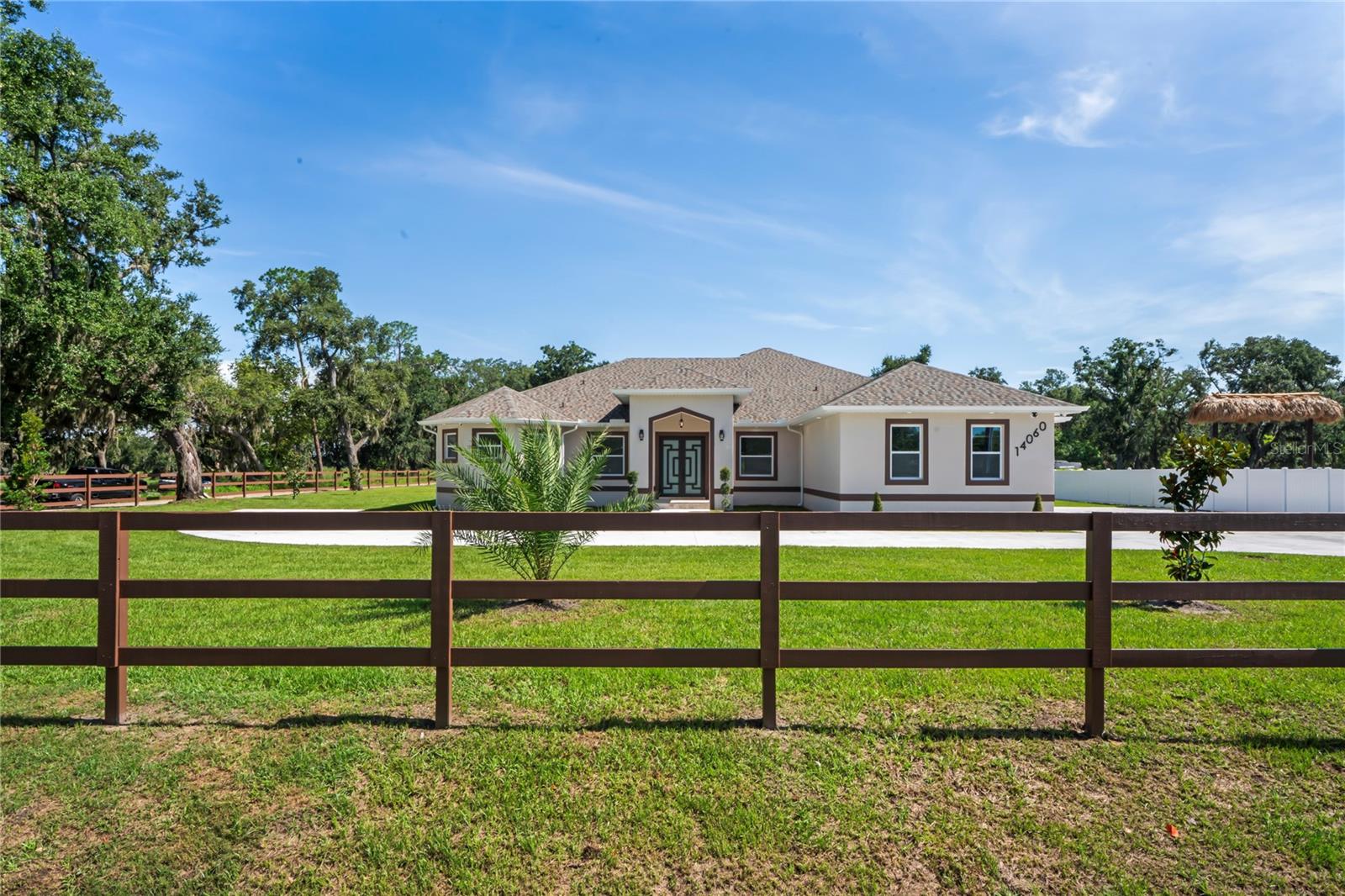 Welcome to Your Florida Home! Newly built in 2025, this stunning modern block home sits on a cleared, fully fenced 1.05-acre lot — beautifully sodded with lush grass, stately palm trees, and a few charming pines for that Florida touch. Step inside through an impressive 9-foot dual door entryway crowned with an elegant chandelier that welcomes you into over 4,600 total square feet of refined living space — including 3,375 sq ft under air with 4 spacious bedrooms and 3.5 luxurious baths. The expansive master suite is truly a private retreat featuring a large his-and-hers walk-in closet, a spa-like bathroom with double vanities, a soaking tub, and a stunning walkthrough triple shower. A second bedroom offers its own ensuite bathroom and walk-in closet, while two additional bedrooms share a convenient Jack-and-Jill bathroom layout — perfect for family or guests. Designed for entertaining, the open floor plan flows seamlessly from the formal living room to a dedicated office with built-in cabinetry, and into the grand family room and gourmet kitchen. The chef’s kitchen boasts an impressive 12’ x 6’ quartz island, extensive white cabinetry, and a complete set of premium KitchenAid stainless steel appliances, including a glass cooktop and sleek range hood. Outside, you’ll love the oversized 3-car garage and expansive wrap-around driveway, providing plenty of parking for family and guests. This is modern Florida living at its finest — spacious, stylish, and move-in ready!