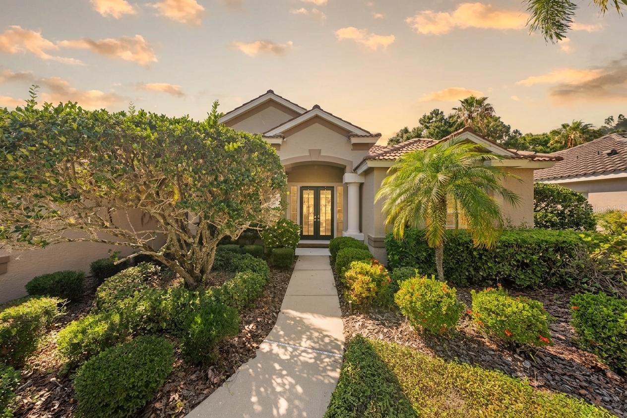 Welcome to this stunning Mediterranean-inspired estate nestled within Edgewater, one of Lakewood Ranch’s most sought-after gated communities. Designed for effortless single-level living, this beautifully appointed four-bedroom, three-bath residence offers a refined blend of timeless elegance, comfort, and the quintessential Florida lifestyle.
Lush, mature landscaping surrounds both the front and rear of the property, creating a private, tropical setting while enhancing the home’s exceptional curb appeal. Enter through charming French doors into a gracious foyer that opens to the formal dining room, where soaring ceilings, crown molding, and arched windows create an inviting atmosphere filled with natural light.
At the center of the home, the spacious open-concept kitchen and great room are thoughtfully designed for both everyday living and entertaining. The chef’s kitchen showcases warm wood cabinetry, a rich mosaic tile backsplash, stainless steel appliances, a new GE microwave (2026), and a Samsung touch-screen refrigerator, along with a center island featuring breakfast bar seating. Seamlessly connected, the expansive family room features a beautiful electric fireplace, creating a warm and inviting focal point for gathering and relaxation. Just beyond, the sunlit breakfast nook overlooks the lanai and pool, making mornings feel like a private retreat.
The luxurious primary suite serves as a peaceful sanctuary, complete with plantation shutters and tranquil views of the pool and outdoor living area. The spa-inspired en suite bath features dual vanities, a soaking tub, and a separate walk-in shower. Thoughtfully designed with privacy in mind, all four bedrooms are positioned in separate areas of the home, creating comfortable and private retreats for family members and guests alike. Three additional bedrooms and two full guest baths provide ample accommodations, while a flexible den, currently designed as an elegant private study with custom built-in bookcases, offers endless possibilities as a home office, library, or additional living space. A dedicated laundry room adds everyday convenience and functionality.
Step outside to your own private outdoor oasis. The screened lanai is designed for year-round enjoyment with inviting lounge spaces, flowing drape panels, and a sparkling pool with attached spa. One of the guest baths serves as a convenient pool bath with direct access from the lanai, enhancing the home's seamless indoor-outdoor lifestyle. Surrounded by mature tropical landscaping and enhanced privacy, this outdoor setting delivers the relaxed luxury and resort-inspired living that make Florida living so exceptional.