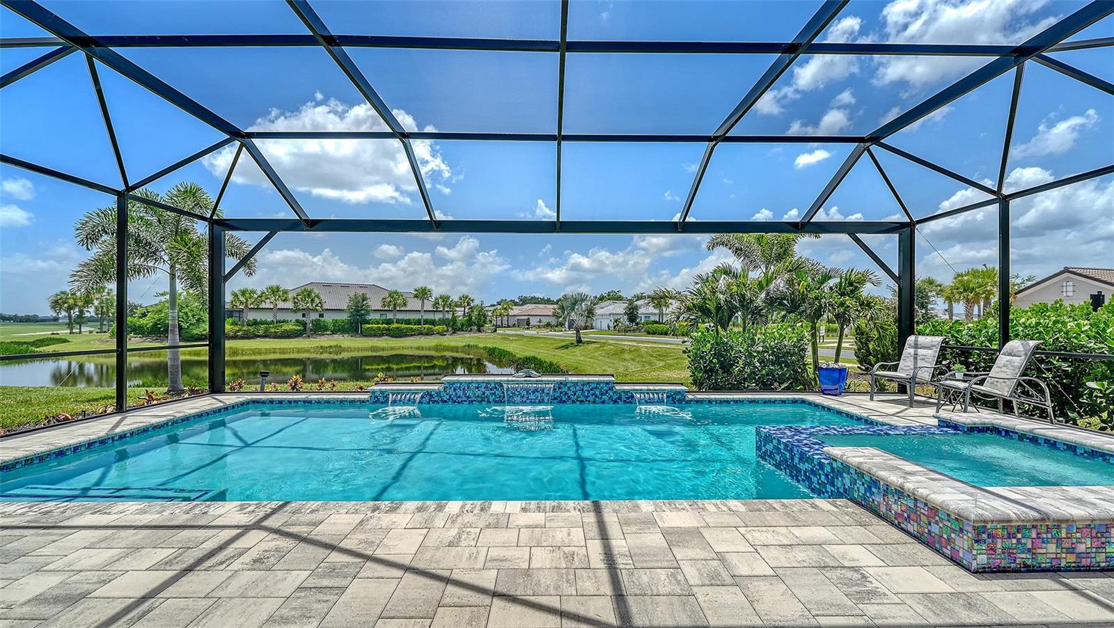 Welcome to 15008 Verole Place in Esplanade at Azario, Lakewood Ranch. This beautifully appointed NON-GOLF Lazio offers a rare opportunity to own one of the community's most desirable combinations of floor plan and homesite. Perfectly positioned on a premium waterfront corner homesite, this residence is tucked away on an intimate cul-de-sac with just 16 homes. With only one adjoining residence and an easement providing additional space and privacy, the setting is truly special. The builder is sold out of Lazio non-golf waterfront homes, making this an opportunity no longer available through new construction.

Offering 2,421 square feet, the home features 3 bedrooms, an open den, 3 baths, and tandem 3-car garage. Structural enhancements include the expanded casual dining area, bay windows in both the primary suite and guest bedroom, and the signature tray ceiling package. The expanded primary suite measures approximately 14' x 20' and includes a separate custom built in walk-in closet.

A light-filled, open floor plan showcases 10-foot ceilings, 8-foot doors, crown molding, impact-resistant windows, Storm Smart motorized screens, designer lighting & ceiling fans, automatic shades, blinds, and sealed wood-look tile flooring throughout the main living areas. The kitchen features upgraded painted cabinetry with soft-close doors and full-extension drawers, quartz countertops, GE stainless steel appliances, including the refrigerator, and an oversized island perfect for entertaining.

The extended covered lanai is designed for year-round enjoyment with a custom vented outdoor kitchen, an oversized saltwater pool and spa with paver deck overlooking tranquil water with a glimpse of the golf course beyond. The desirable southwest rear exposure provides all-day sunshine across the pool and spectacular Florida sunsets.

Additional upgrades include a Lutron smart lighting and alarm system, Aqua Pure water softener, whole-house lightning surge protection, and a Westinghouse 14.5 kW remote-start tri-fuel generator with a professionally installed 50-amp inlet.

Esplanade at Azario offers a true resort lifestyle with a spectacular pool, Bahama Bar, Culinary Center, fitness center, spa, tennis, pickleball, bocce, dog park, walking trails, and an active social calendar. Owners also have the opportunity to purchase an Annual Golf Membership (subject to availability), providing championship golf without mandatory deeded golf fees.

With its premium homesite, exceptional finishes, and outstanding location, 15008 Verole Place offers an extraordinary opportunity to enjoy luxury living in one of Lakewood Ranch's premier resort communities.