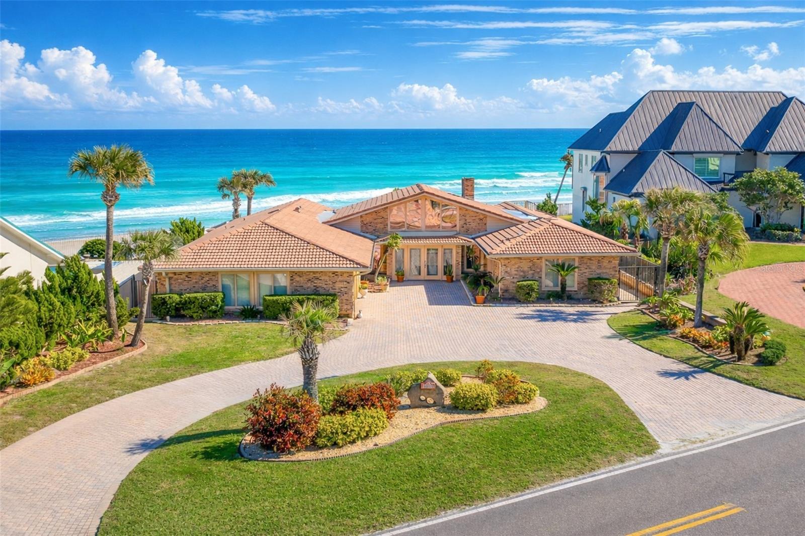 SPECTACULAR OCEANFRONT POOL HOME WITH MAGNIFICENT VIEWS LOCATED ON AN EXCEPTIONAL 100' x 200' ESTATE PARCEL WITH SEAWALL ON THE PRISTINE ''NO DRIVE'' BEACH OF PONCE INLET! This beautifully designed ranch style pool home features 3,238 sq. ft of luxurious living area consisting of 4 bedrooms plus an office and 4 full bathrooms. A spacious open split-bedroom floor plan makes this home perfect for everyday comfort and for entertaining guests. Outdoors, the home is a private coastal retreat featuring a spacious covered lanai with an in-ground heated spa and a dramatic 10' deep oceanfront pool and expansive patio, all designed for relaxing and entertaining while enjoying breathtaking, unobstructed ocean views! Sturdy brick construction for easy maintenance combined with a barrel tile roof, some impact windows, hurricane shutters & two HVAC systems provide energy efficiency and peace-of-mind.  Step inside this lovely home through the double door entryway and your eyes focus on the breathtaking views of the azure Atlantic Ocean!! The expansive great room boasts a wall of sliding glass doors, transom windows and a classic tongue and groove vaulted wood ceiling creating an elegant coastal atmosphere. A cozy wood burning corner brick fireplace adds charm and warmth to the home's refined ambiance. The fully-equipped kitchen has awesome ocean views, a beam ceiling, Corian countertops, wood cabinetry, breakfast bar & built-in desk. The huge primary suite is a private oceanfront retreat with two generous walk-in closets and a spa-inspired bathroom. Three spacious en-suite guest bedrooms (each with a walk-in closet) plus a dedicated office provide maximum comfort and functionality. An enormous inside laundry room has plenty of storage and workspace. The huge garage has shark flooring and is roughly 27' x 29' with work bench area, and the expansive circular paver driveway provides ample parking for friends & family. Ponce Inlet is a peaceful seaside community located between the Atlantic Ocean and the Intracoastal Waterway known for its pristine beaches, scenic waterways and iconic lighthouse. This charming coastal enclave features an expansive shoreline of compact sugar sand perfect for walking, biking, jogging or just relaxing. There's also many waterfront restaurants, tiki bars, parks, nature trails, marinas, charter fishing, Marine Science Center, fishing, boating, surfing, kayak/canoe, dog park/beach and much more! Homes of this caliber are limited  SCHEDULE YOUR PRIVATE SHOWING TODAY. Measurements are approximate.