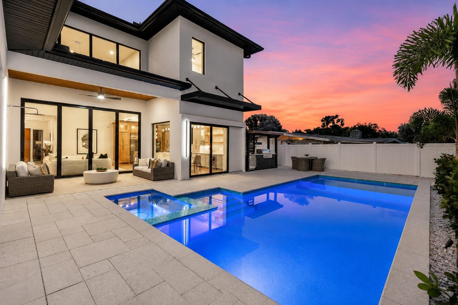Not just another house but a carefully curated masterpiece by Segatto Property Solutions Inc. Come experience a blend of modern luxury, sophisticated design, and effortless Florida living in this stunning, newly completed custom residence. This move-in-ready, two-story block home offers four bedrooms and 4.5 baths plus an office, thoughtfully designed with impeccable attention to detail, soaring ceilings, and an open-concept layout ideal for everyday living and elevated entertaining. From the moment you enter, you’re greeted by 10-foot ceilings throughout, with dramatic 22-foot ceilings in the great room that create a grand, light-filled space. The office and primary suite also feature 12-foot ceilings, adding an extra layer of refinement and comfort. The designer kitchen is the heart of the home, showcasing quartz countertops, all Moen fixtures in bronze gold, and matte black, a premium KitchenAid appliance package, custom cabinetry, walk-in pantry, and an oversized island that flows seamlessly into the great room and dining areas. Expansive sliders open to the outdoor living space, delivering the ultimate indoor-outdoor lifestyle. Go outside to your fully fenced, private oasis featuring a heated saltwater pool, a fully equipped covered outdoor kitchen with grill and refrigerator, and an outdoor shower, ideal for entertaining or unwinding in total privacy. The first floor primary suite offers a spa-like retreat with luxurious finishes, generous space and a beautifully appointed bath, featuring dual shower heads, free-standing tub and an oversized walk-in closet. Upstairs, two additional en suites and a versatile loft area with a wet bar provide the ideal setting for a media room, lounge or guest retreat. Practicality meets luxury with a well-appointed first-floor laundry room featuring LG smart washer and dryer, additional built-in storage and a utility sink. Personalize your new home with a Builder Allowance of $50,000 to be used for your closet buildouts. Every detail of this home reflects quality craftsmanship and modern elegance, delivering the feel of a high-end model home without the wait. Ideally in Arlington Park, near shopping, dining, beaches and everything Sarasota has to offer, this exceptional home is ready for its first owners. Schedule your private showing today. Homes of this caliber, completed and move-in ready, are a rare opportunity.