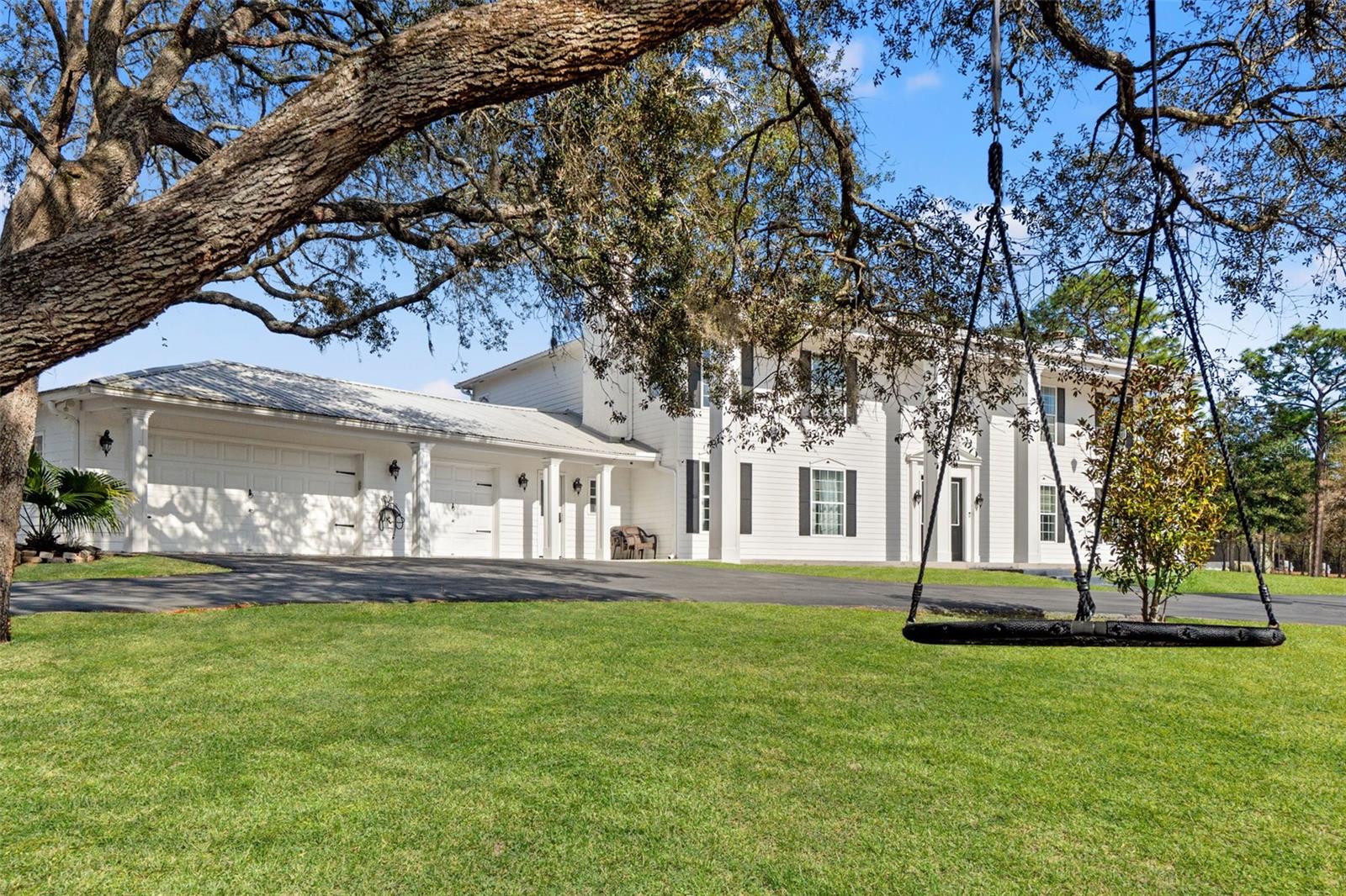 Inspired by classic Colonial architecture and the grandeur of the White House, this extraordinary estate offers refined living on a private 2.40-acre setting with no HOA, no CDD, and AR2 Agricultural Residential zoning—giving you space, freedom, and flexibility. With 4 bedrooms, a private office, 3 full baths, 2 half baths, and 4,240 square feet of living space (6,334 total square feet including the garage), every detail has been thoughtfully designed for both elegance and comfort.From the moment you arrive, the home makes a statement. A gated, fully enclosed property opens to a stately residence where a dramatic two-story foyer welcomes you inside. A breathtaking chandelier cascades light over a custom quartz staircase with modern cable railing, setting the tone for a home that blends timeless design with contemporary sophistication. Formal sitting and dining rooms frame the entry, ideal for entertaining or quiet moments alike.At the heart of the home is a chef’s kitchen that is nothing short of exceptional. Designed for both function and beauty, it features premium Dacor appliances, including double ovens, a 48-inch dual-fuel steam range with griddle and six-burner gas cooktop, double-column refrigeration, built-in freezer drawers, a Dacor dishwasher, and a Miele espresso maker. A generous quartz island anchors the space, complemented by a walk-in pantry, butler’s pantry, built-in ice maker, and a charming eat-in nook overlooking the pool through a sunlit bay window.The living spaces are equally inviting, with luxury vinyl flooring, custom finishes, and three wood-burning fireplaces that add warmth and character throughout. A custom home theater living room elevates entertainment, featuring professionally installed KEF surround sound, in-wall and in-ceiling speakers, a subwoofer, and Denon receiver—all seamlessly controlled by a Savant remote. (Projector and screen available separately.)Upstairs, four spacious bedrooms provide comfort and privacy. Two guest suites offer en-suite bathrooms and custom closets, while the primary suite is a true retreat. This serene space includes a private balcony overlooking the pool, a spa-inspired bath with dual vanities, rainfall shower, and garden tub, plus an expansive custom closet complete with center island and a secure armory room.Security and peace of mind are paramount, with a motorized main gate, service gate, ADT security system, full camera coverage, and a dedicated safe room with surveillance monitors.Modern conveniences abound, including two new 5-ton Trane AC units, a tankless water heater, Generac generator with 350-gallon propane tank, water softener, new well pump and tank (2024), EV or camper 30-amp hookup, oversized laundry room, and a pristine epoxy-floored garage with craftsman workbench.Step outside to your own resort-style oasis. A heated Pentair pool with waterfall is surrounded by refinished pavers, while a gazebo invites evening gatherings and a greenhouse offers year-round gardening. Every element of this estate has been curated to offer luxury, privacy, and a lifestyle that feels both grand and effortlessly livable.