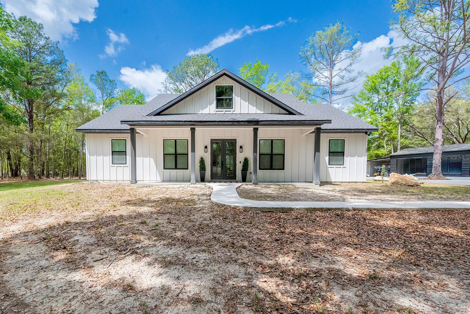 Welcome to your private North Florida retreat in Fort White! This stunning 3 bedroom, 2 bath,  home sits on 5 beautiful acres, offering the perfect blend of modern luxury and peaceful country living. A gated entry welcomes you in, leading down a winding asphalt driveway that sets the tone for the privacy and elegance this property provides. Step inside to an open-concept floor plan designed for both comfort and entertaining. The home features soaring 10-foot ceilings, oversized 8-foot doors and entryways, and an inviting electric fireplace that creates a warm focal point in the living space. The luxury kitchen is a true showstopper, complete with a large island featuring a built-in beverage cooler, ample cabinetry, and high-end finishes—perfect for hosting or everyday living. The spacious primary suite is a retreat of its own, highlighted by a spa-like bathroom featuring a massive 10-foot walk-in shower with dual shower heads, creating a true resort-style experience at home. Throughout the home, you’ll find beautiful upgrades and thoughtful details that elevate every space. Outside, the property continues to impress with a large detached 3-car garage and additional carport, offering endless possibilities for a workshop, storage, or hobby space. There’s also a 30-amp generator inlet box already in place, adding convenience and functionality for your lifestyle. Located just minutes from renowned natural attractions like Ichetucknee Springs State Park and Ginnie Springs, and a short drive to High Springs and Lake City, this property offers easy access to outdoor recreation, dining, and everyday amenities.