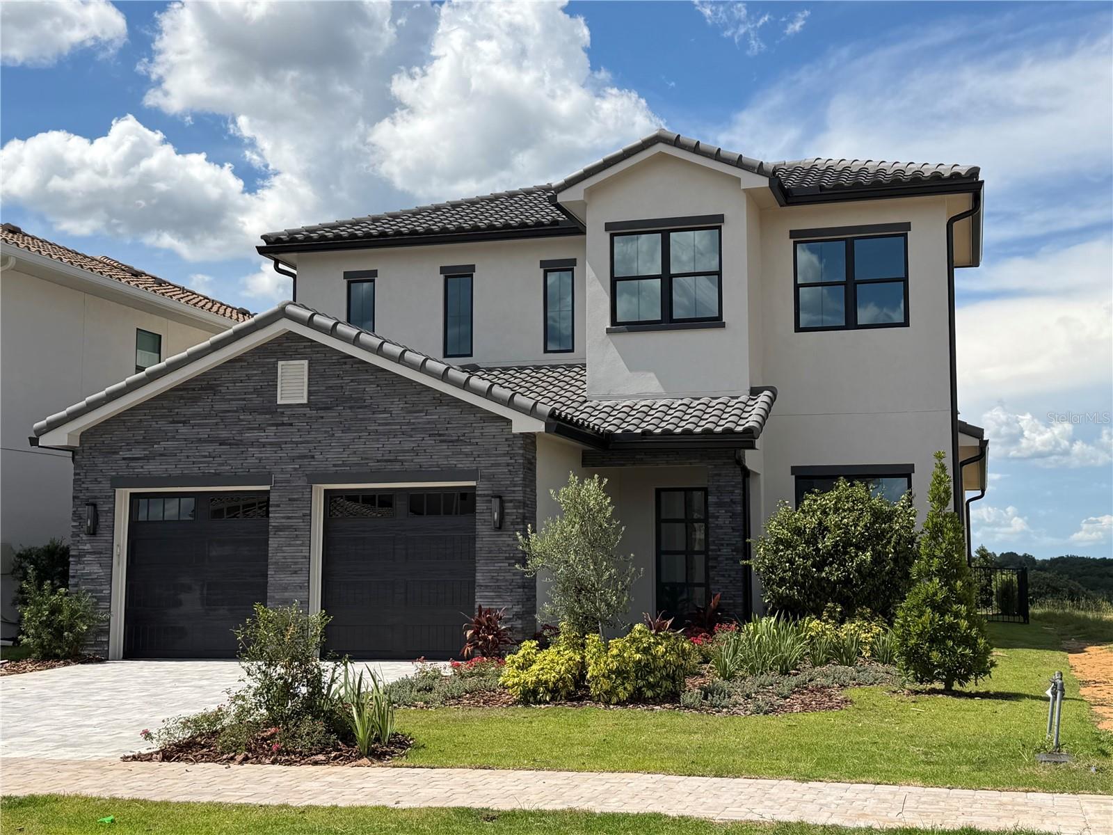 Under Construction. Designed for those who appreciate thoughtful architecture and effortless living, this new construction Golf Villa by Vogel Homes makes a striking first impression within the gates of Bella Collina. Clean lines, layered textures, and bold window design create a timeless exterior that feels both modern and welcoming as you arrive.

Step inside and discover spaces that invite connection and calm. The heart of the home opens gracefully, where the kitchen, dining, and family rooms come together in a setting meant for everyday moments and memorable gatherings alike. The kitchen is beautifully appointed with designer cabinetry, premium finishes, and a generous island that anchors the space - perfect for morning coffee, casual meals, or evening entertaining. Natural light fills the interiors, creating a warm, airy atmosphere throughout.

The primary suite on the main level offers a quiet escape, with a spa-inspired bath and walk-in closet designed for comfort and ease. Additional guest suites provide privacy for family and friends, while the upper level unfolds into a spacious loft and game room complete with a wet bar - ideal for movie nights, hosting, or simply unwinding. Upstairs bedroom suites and an outdoor deck extend the living experience even further.

Outdoor living is a natural extension of the home, featuring a covered lanai, summer kitchen, resort-style pool and spa - an inviting backdrop for long afternoons and relaxed evenings under the Florida sky.

As a resident of Bella Collina, enjoy access to a private, gated community centered around a Sir Nick Faldo-designed championship golf course, The Club at Bella Collina, spa and fitness facilities, tennis and pickleball courts, dining, and a vibrant social lifestyle.

Developer will Defer the $40,000 Sports Membership Deposit. A valuable opportunity to step into the Bella Collina lifestyle. Call today for details.