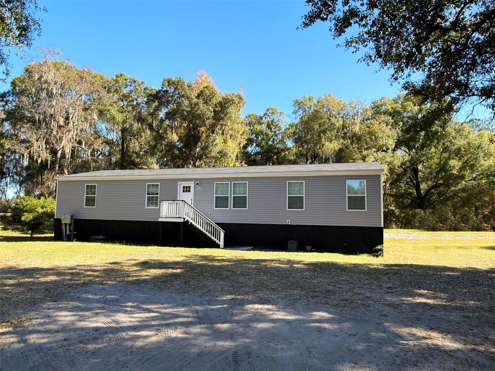 This beautifully maintained modular home 4-bedroom, 2-bath, built in 2022, sits on 7 sprawling acres just outside the city limits along State Road 16, convenience, and wide-open space. Step inside to an inviting split floor plan designed for both comfort and function. The open-concept kitchen is the heart of the home, offering cabinetry, generous counter space, and seamless flow into the dining and living areas—ideal for gatherings and everyday living. The primary suite provides a relaxing retreat, with double sinks, tub and shower and a large walk-in closet. Three additional bedrooms create flexibility for family, guests, or a home office. The 7 acres with mature trees and privacy, creates plenty of room for animals, gardening, outdoor hobbies, or simply enjoying the quiet beauty of country life. There is also a 12x28 open shed. Ready for you to make it your own. Easy commute to Gainesville and Jacksonville!
