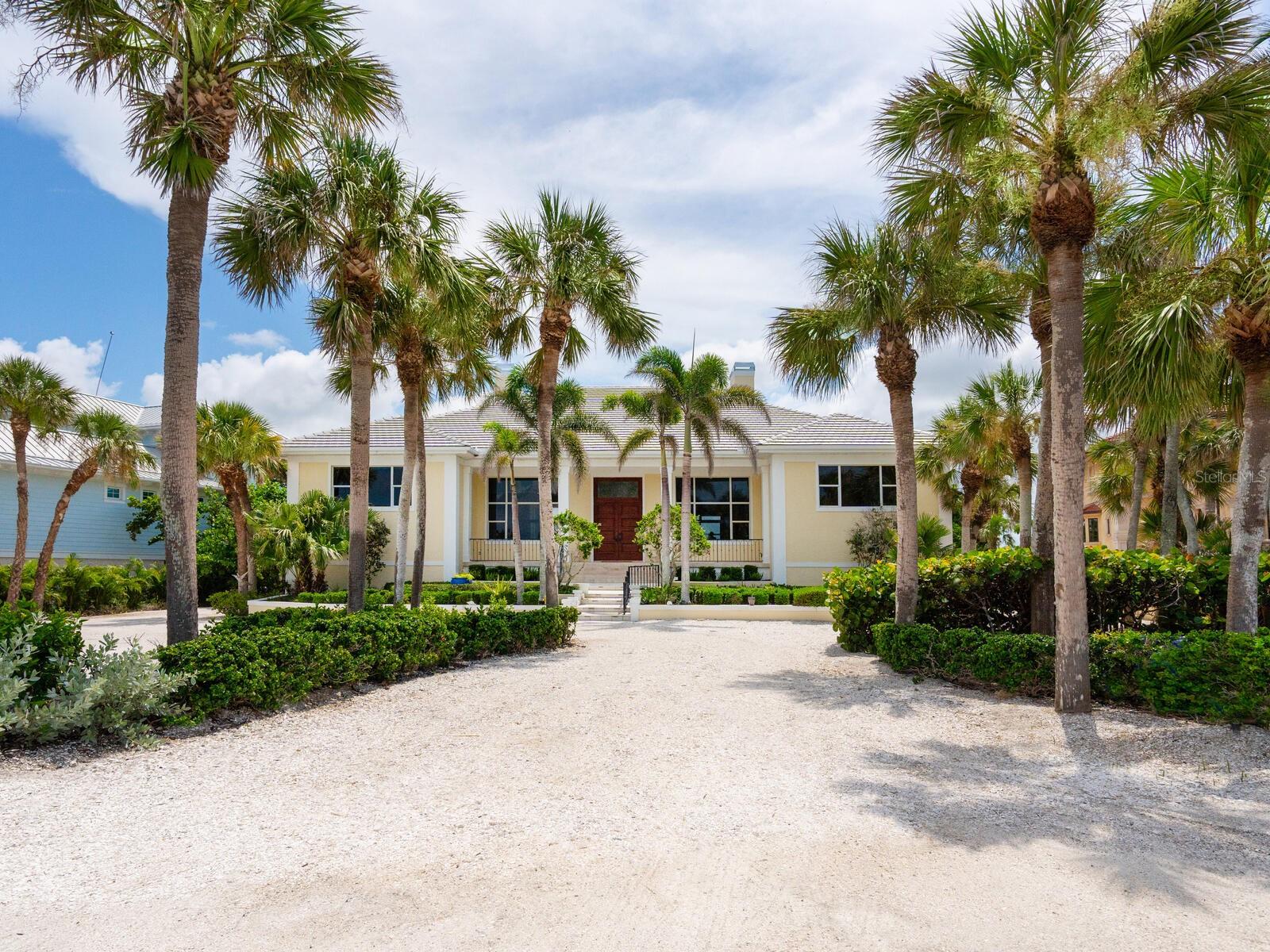One or more photo(s) has been virtually staged. A waterfront paradise dream—an exquisite Gulf-to-Bay estate set on 1.4 tropical acres along the shores of Casey Key. This stunning two-story home, built in 1999, with solid concrete block construction on pilings, offers 4,460 square feet under air (11,189 total square feet), five bedrooms, and 4.5 baths, including a luxurious owners’ suite. Property highlights include an impressive 18-foot base flood elevation with impact windows on the Gulf front west side and retractable shutters on the east. Enjoy travertine and oak floors, soaring ceilings and refined column millwork. The flexible layout provides plenty of room for family and guests alike, home office space, a cozy den and elevator shaft ready for convenience. Four-car side-entry garages, workshop plus extensive non-conforming storage below the main living area stayed dry and impervious to recent storms. An outdoor oasis lies between 150 feet of private sandy beach frontage with a grandfathered cabana and 150-foot bay frontage featuring a protected intracoastal boat basin set just beyond the pool and spa. Florida native plantings create a serene backdrop throughout the grounds. Wake to sparkling Gulf breezes, take private beach strolls or dock your boat on the intracoastal basin. Host elegant gatherings throughout the open main living areas, enjoy casual living on the screened porch, or retreat to the secluded owners’ suite—this home blends relaxed coastal living in one of the prime Gulf-to-Bay locations—luxury, privacy and panoramic waterfront views on Casey Key await your personal touch and modern updates to make it your own.