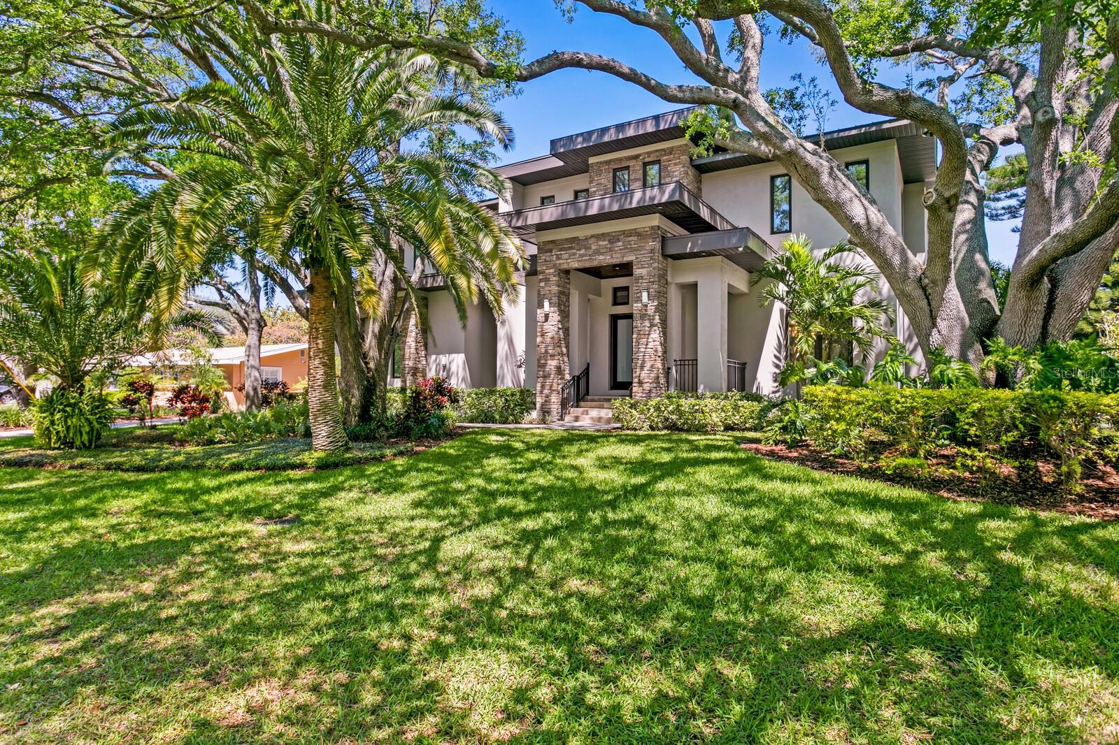 Come home to South Tampa Newer 2016 built custom construction. A tropical waterfront haven awaits in this Transitional Modern architecture on the canal moments to the open waters of Tampa Bay. Built to newer building codes with exterior concrete block construction, impact windows/doors, and elevated structure for flood risk reduction and favorable insurance premiums. Offering refined finishes and features on .36 acres, you’re greeted by mature landscape and pristine grounds to the double door entry and light-filled living spaces, hardwood floors and elevated appointments throughout. Boasting a welcoming grand two-story foyer entry, with lounge and glass-enclosed wine room, a formal dining room with tray ceiling, beautifully appointed chef’s kitchen overlooking the family room and water beyond. The bright kitchen features custom cabinetry to the ceiling, a large island and pantry, top-of-the-line Wolf/Subzero appliances, butler’s pantry and breakfast area, overlooking the family room with extensive built-ins (library rail) and fireplace with access to the covered terrace for dining and entertaining. The first level also includes an in-law suite with sitting area and ensuite bed/bath, and generous laundry room with convenient drop zone storage. The second level provides 4 guest bedrooms, (3 ensuite), Bonus Room (with soundproofing), second level laundry and a waterfront primary suite retreat.  Enjoy access to a generous covered terrace from the primary suite, along with a sitting area, dual closets and a luxurious master bath with soaking tub and walk-in-shower. The perfect oasis awaits outdoors with a waterfront saltwater pool, spa and expansive paver pool deck, an inviting covered lanai, outdoor kitchen, dock and covered 13K lb boat lift. Additional appointments include custom cabinetry, vaulted ceilings, thermal windows, metal roof and 3-car garage with new epoxy flooring in this quiet South Tampa neighborhood. A prime central location provides excellent shopping, dining and recreation opportunities convenient to International Plaza, West Shore Plaza and Hyde Park Village. Have the very best of Tampa lifestyles in the highly sought-after Plant High School District, minutes to Downtown Tampa, Tampa Riverwalk, sports venues, Tampa International Airport and outstanding Gulf beaches.