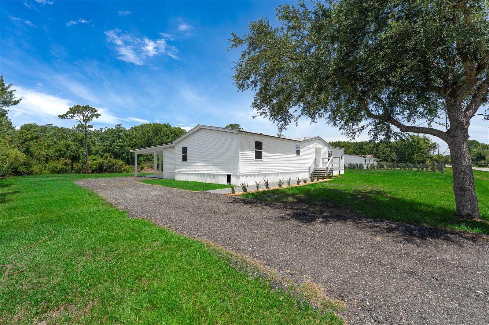 Completely remodeled and move-in ready, this stunning 4-bedroom, 3-bath home sits on 2.45 private acres with no HOA and no recurring fees, offering the perfect blend of modern updates and country living. Every detail has been thoughtfully renovated, including a metal roof on both the home and attached covered carport, brand-new HVAC, windows, stainless steel appliances, LED lighting, wall-to-wall ceramic tile flooring, white shaker cabinetry, and elegant white quartz countertops throughout the kitchen and all bathrooms. The open-concept split floor plan provides both functionality and privacy, with spacious living areas centered around a cozy wood-burning fireplace. The owner's suite features an adjoining flex room ideal for a home office, nursery, fitness space, or sitting room. The luxurious primary bath includes a soaking tub, walk-in shower, dual-sink vanity, linen closet, and generous his-and-hers closets. A private guest suite with its own en-suite bath is perfect for visitors or multi-generational living, while two additional guest bedrooms share a beautifully updated third full bathroom. An indoor laundry room includes a washer and dryer for added convenience. Outside, you'll find plenty of room to spread out, expand, garden, or park your RV, boat, trailer, and other recreational vehicles. The attached covered carport provides sheltered parking, while the expansive acreage offers exceptional privacy and endless possibilities. Conveniently located with easy access to the Florida Turnpike and other major roadways, this property delivers the best of peaceful living without sacrificing accessibility.