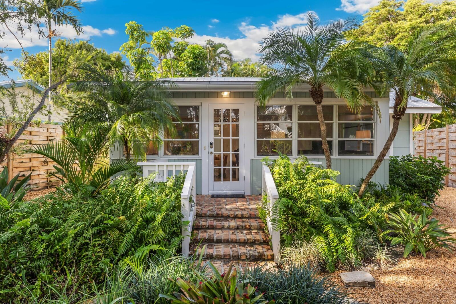 A quintessential Boca Grande cottage located in the heart of the historic village. This charming cottage offers two bedrooms, two baths and a heated saltwater pool. Beautifully situated behind two entry gates, a brick paver path surrounded by lush landscaping leads you to the front sitting area with built-in benches. Stepping inside, you will appreciate the window-filled sitting room with abundant natural light. This is an ideal spot for morning coffee. Just beyond the sitting room, is the living area where you will immediately appreciate the thoughtful improvements that have been made while preserving the historic character of this home. With recessed lighting, warm wood flooring, and a built-in window seating area. The cheerful kitchen is just off the living room. It features a small bar area and access to the patio and pool. The master bedroom, with an ensuite, offers French doors leading out to the pool, recessed lighting, and a beautiful bay window. The guest suite is across the hall and features charming built-in window seating. The brick-paved patio area has a heated pool lined by greenery, and the new fencing provides a private, tranquil space for gatherings and intimate dinners. If you have been searching for a cozy cottage in the village, steps away from dining, shopping, and the beach, this is it!