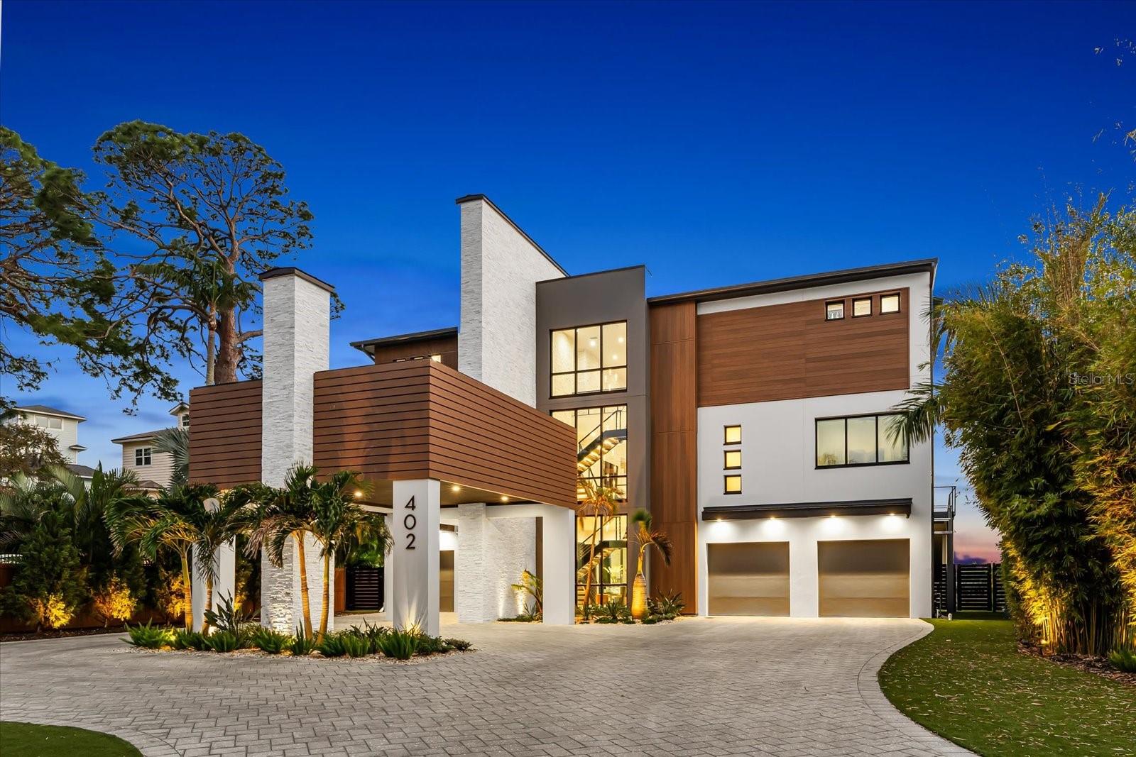 Welcome to 402 Hillsborough Street, a custom-built 2023 waterfront residence offering a rare combination of scale, privacy, and direct access to multiple water bodies including Boggy Bayou, the Intracoastal Waterway, and the Gulf of America. Situated on a 0.68-acre lot within a private gated community, this property features approximately 5,196 square feet of heated living space and nearly 9,700 total square feet, thoughtfully designed across three levels with elevator access.

This five-bedroom, four full and one half-bath home showcases a contemporary architectural design with block construction, metal roofing, and impact-rated windows. Interior features include engineered hardwood and porcelain tile flooring, high and vaulted ceilings, tray ceilings, an open floor plan, and a kitchen-family room combination designed for both daily living and entertaining. The primary suite is located on the third level and includes two walk-in closet and expansive proportions.

Additional interior highlights include a bonus room, great room, sauna, electric fireplace, upper-level laundry room, and smart home features including security system, cameras, and touchless entry. The home is equipped with central air, natural gas, tankless water heater, and owned solar panels.

Outdoor living is enhanced by a private heated pool and spa, multiple balconies and patios, irrigation system, and mature landscaping. The property offers approximately 600 feet of combined water frontage and includes a 2023 composite dock suitable for fishing and recreational water use such as paddleboarding and kayaking.

Parking is extensive with a four-car attached garage, additional two-car carport, circular driveway, EV charging capability, and ample off-street parking. Community amenities include gated access and maintained private roads with HOA services covering exterior maintenance, grounds, and common areas.

Located in unincorporated Palm Harbor near golf courses, marinas, and top-rated schools, this property presents a unique opportunity to own a newly constructed waterfront home with expansive water views and access.