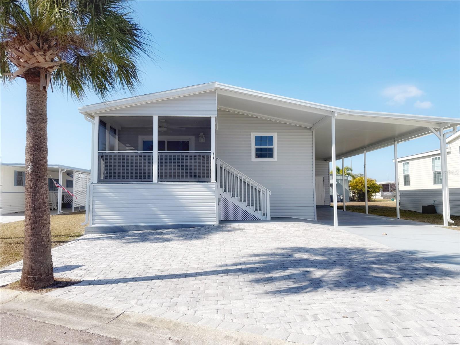 Located in the sought-after Caribbean Isles, this beautifully maintained 2021-built 2-bedroom, 2-bath home offers modern construction, thoughtful design, and relaxed Florida living. Built to the highest code and HUD specifications, this home provides peace of mind along with timeless style. The open-concept kitchen and living area is bright and inviting, featuring neutral décor, attractive lighting fixtures, ceiling fans, and space for both a dining table and casual seating at the kitchen island. The home is partially furnished and impeccably cared for, making it easy to move right in. The primary bedroom includes an ensuite bath, while the second bedroom is ideal for guests or a home office. A washer and dryer are conveniently located in the hallway. As you step outside to the screened front porch, the perfect spot to enjoy your morning coffee while watching the sunrise, note the shaded sliding glass doors. You'll also note the upgraded plantation, shutters throughout the home on both the  sliding door and windows. The spacious carport is tall enough to accommodate a boat, and the community also offers on-site boat and RV storage. Caribbean Isles is a pet- and golf-cart-friendly, gated 55+ community designed for both seasonal and full-time residents, featuring resort-style amenities, an active social calendar, and a true waterfront lifestyle with canals leading to Tampa Bay.
Whether you’re looking for a refined winter retreat or a year-round home, this nearly new residence delivers comfort, quality, and an exceptional coastal lifestyle.